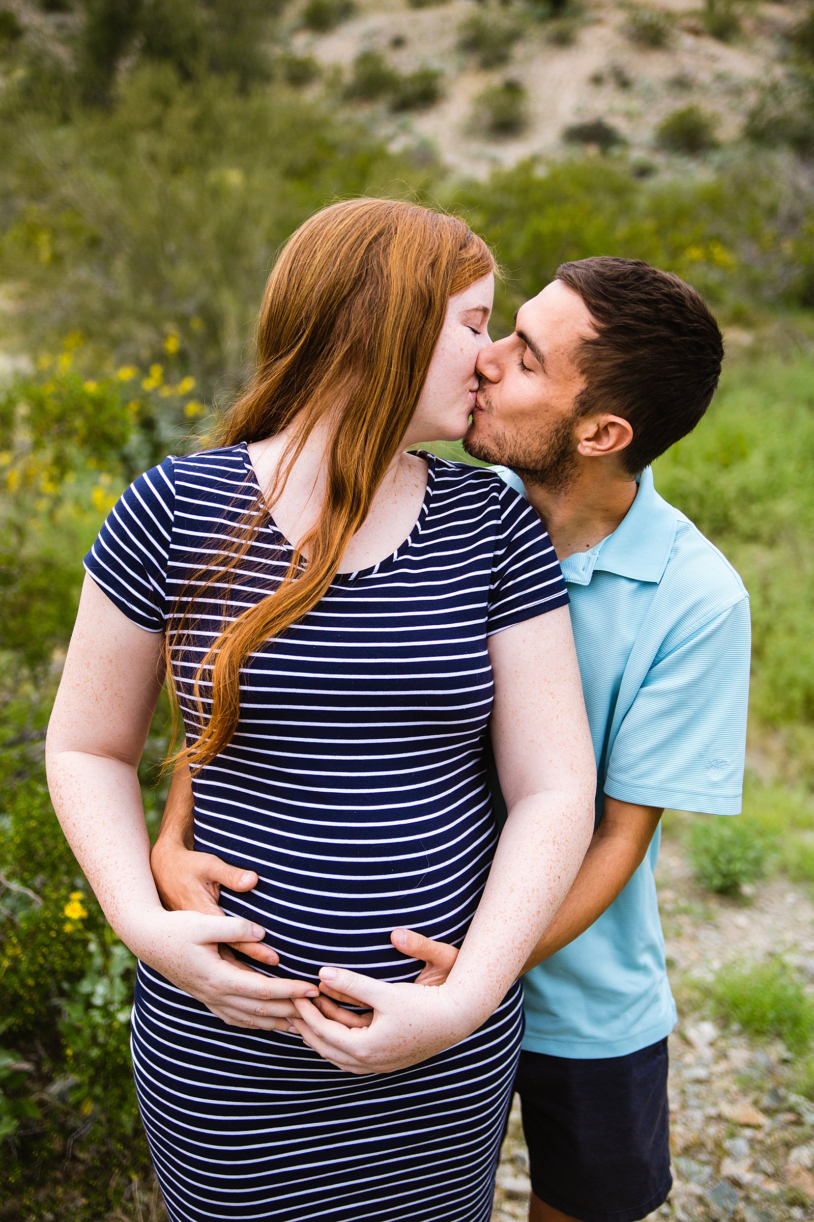Couple share a kiss during their Phoenix maternity session by Arizona wedding photographer PMA Photography.