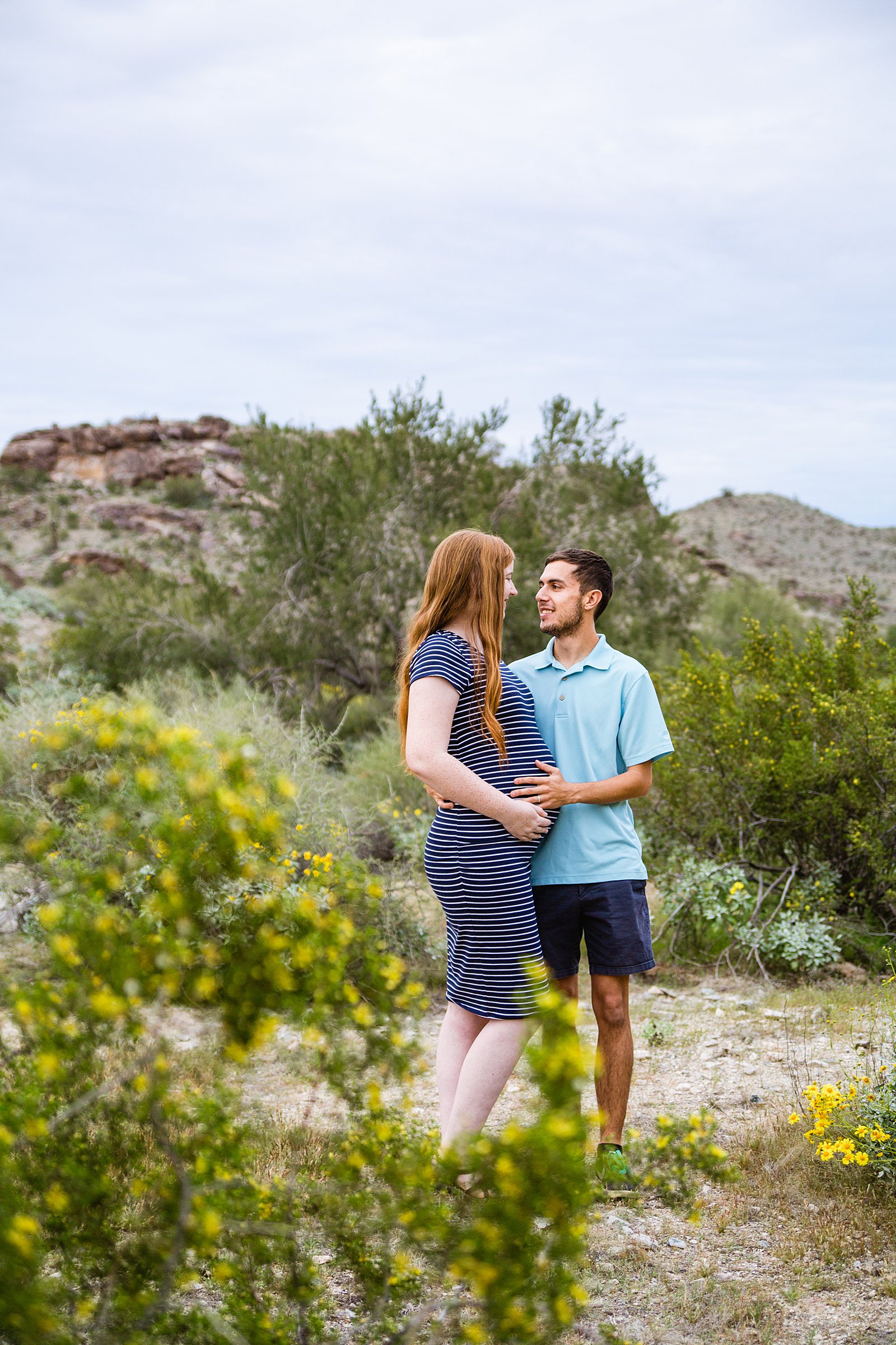 Couple look at each other during their Pima Canyon maternity session by Phoenix wedding photographer PMA Photography.
