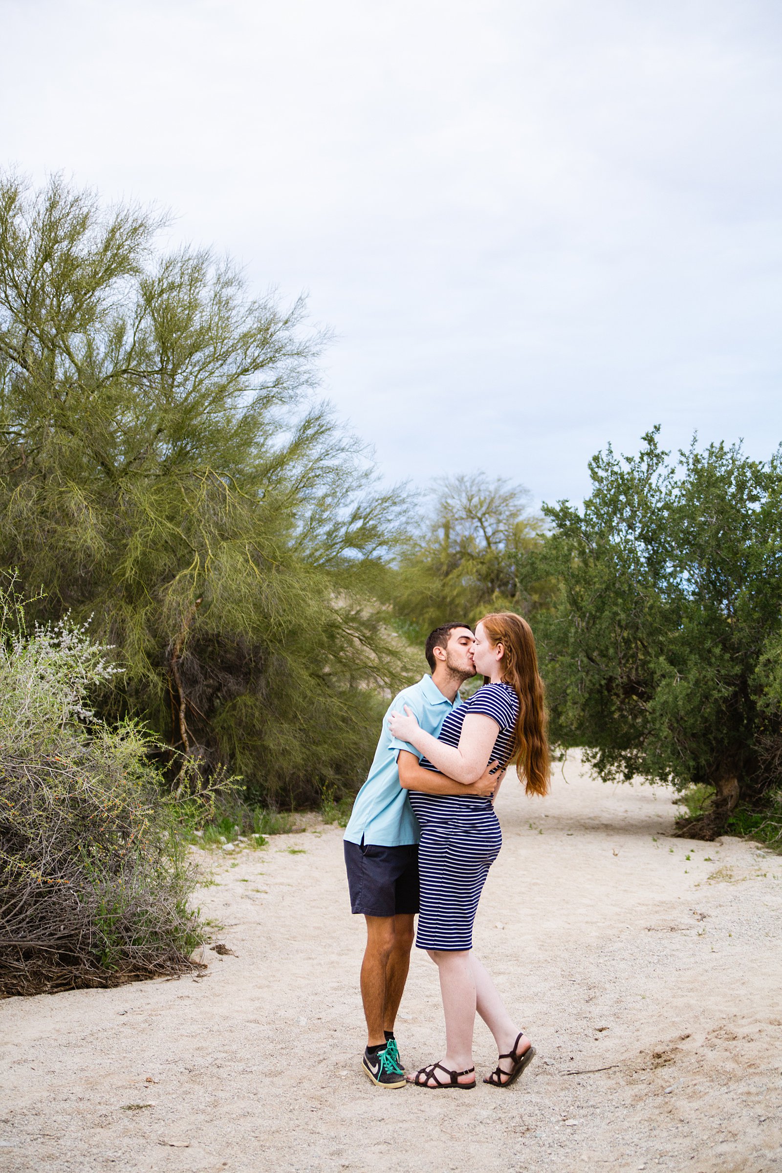 Couple share a kiss during their Pima Canyon maternity session by Phoenix wedding photographer PMA Photography.