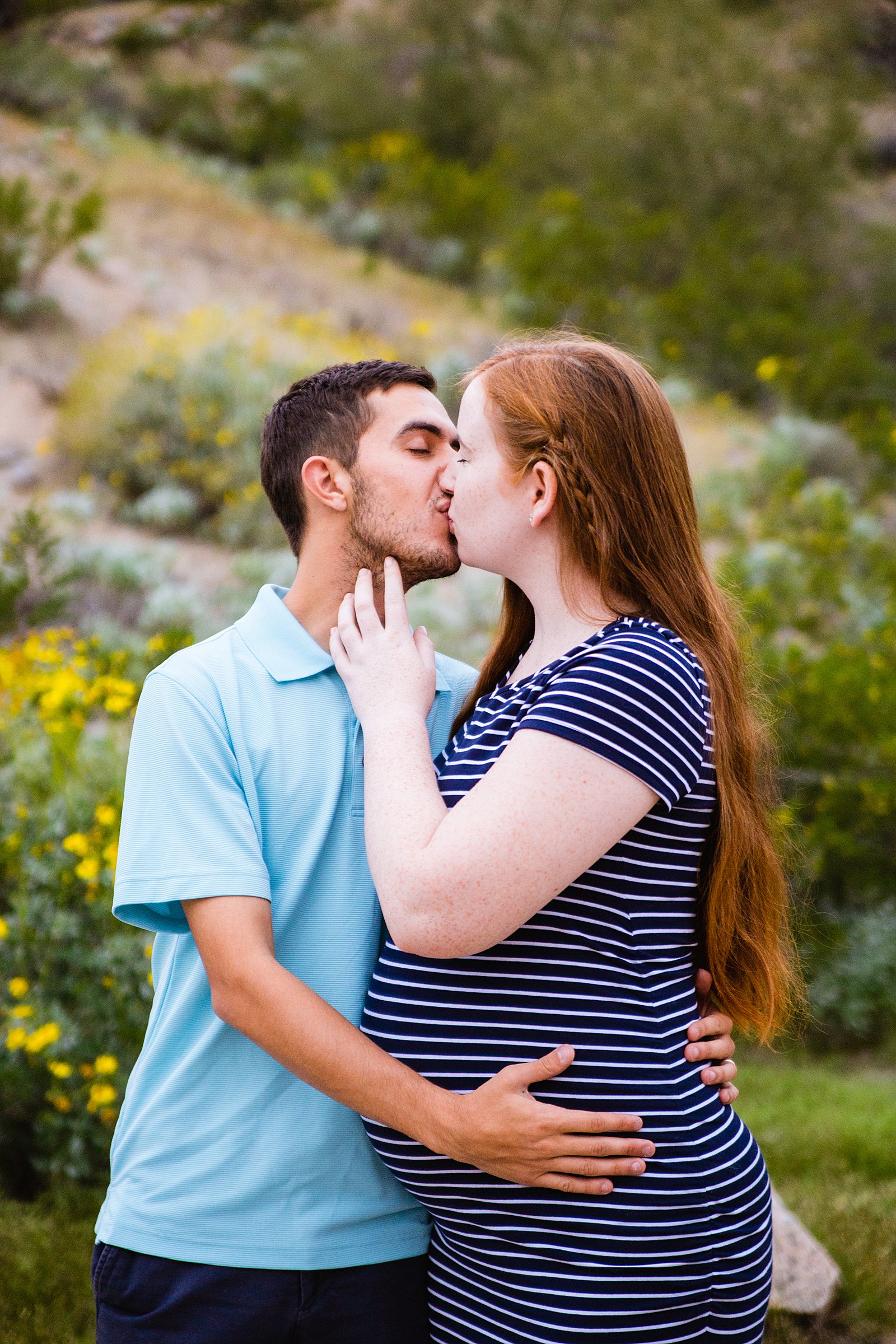 Couple share a kiss during their Pima Canyon maternity session by Phoenix wedding photographer PMA Photography.