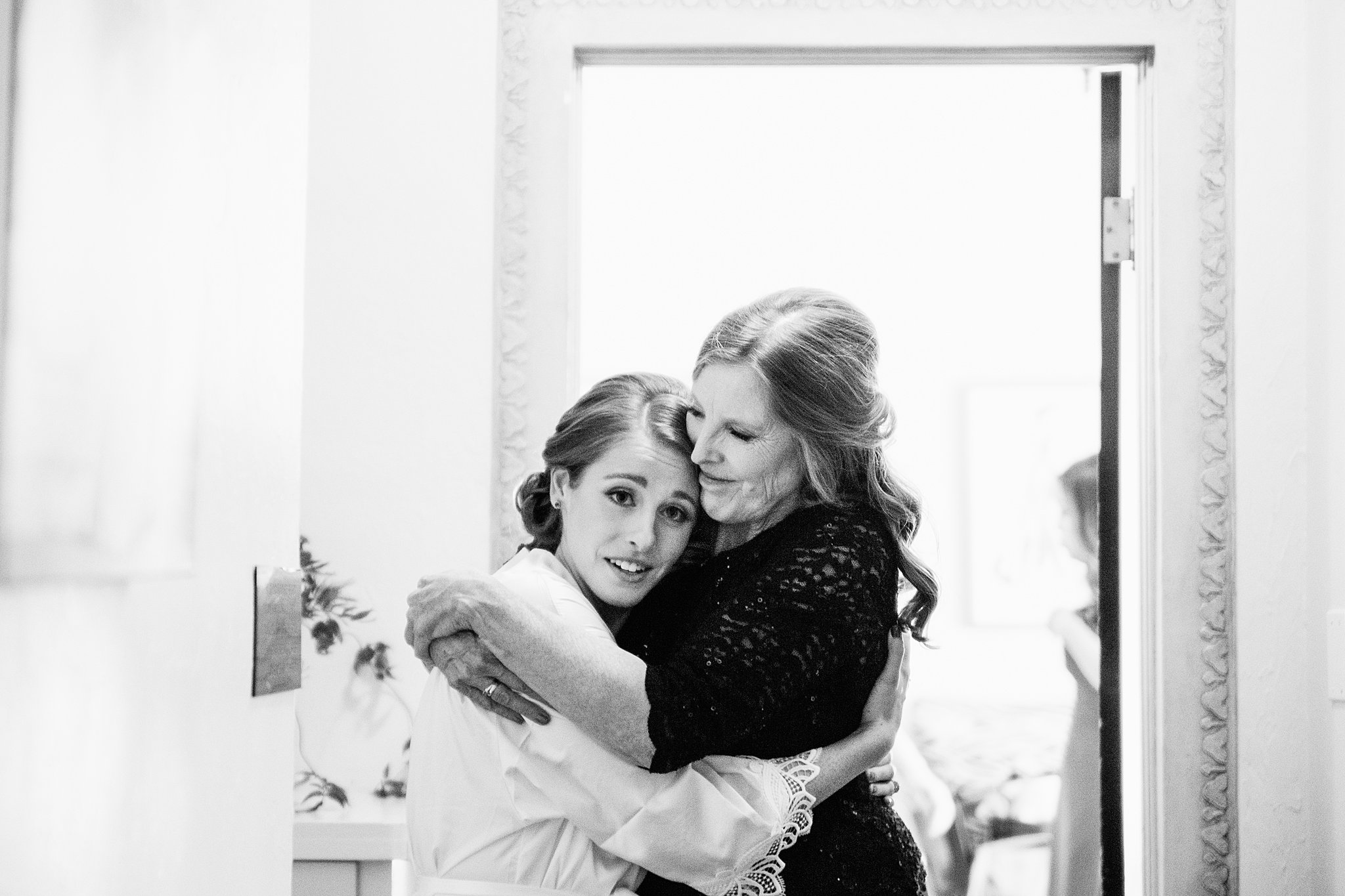 Bride and her mother hug before putting on her wedding dress by Phoenix wedding photographersPMA Photography.