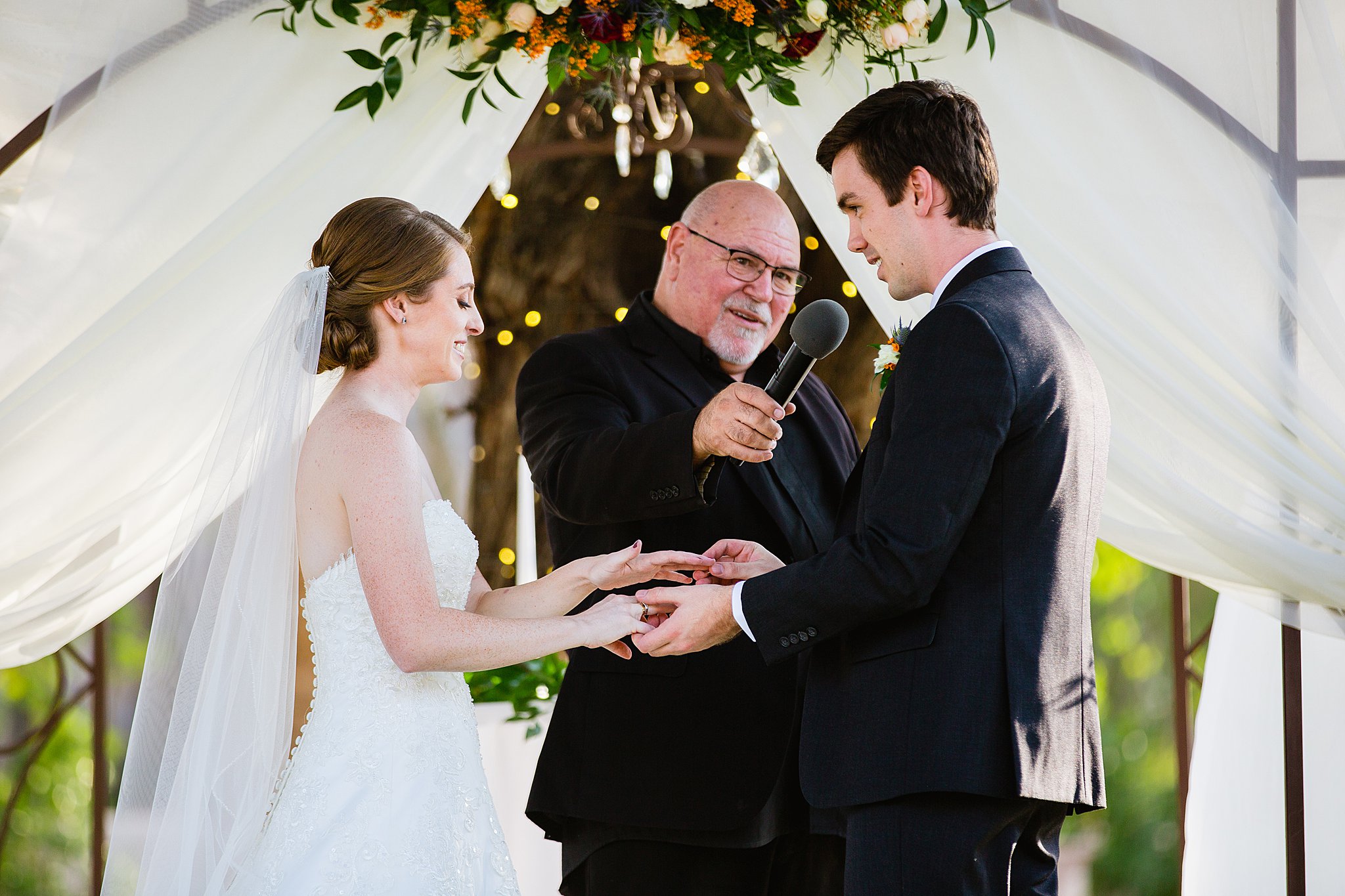Bride and Groom exchange rings during their wedding ceremony at Secret Garden Events by Arizona wedding photographer PMA Photography.