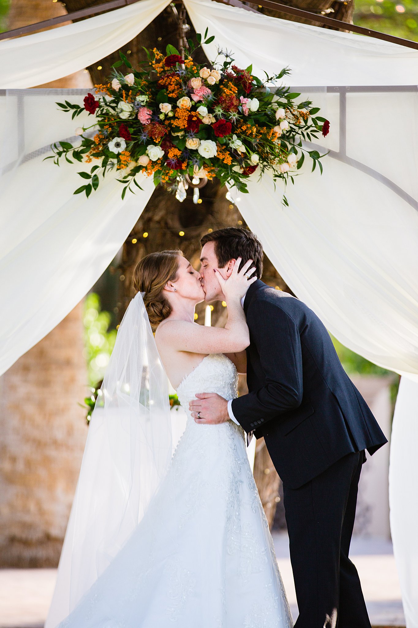 Bride and Groom share their first kiss during their wedding ceremony at Secret Garden Events by Arizona wedding photographer PMA Photography.