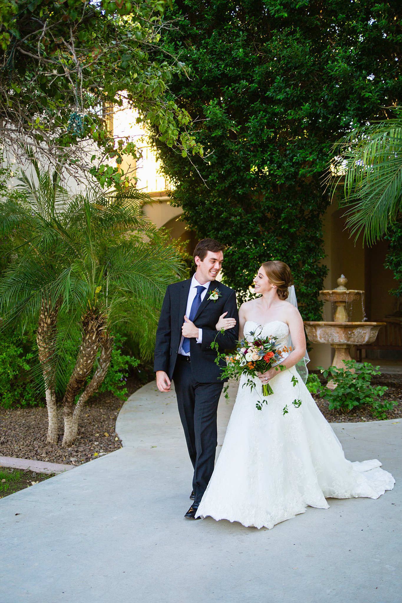 Bride and Groom walking together during their Secret Garden Events wedding by Arizona wedding photographer PMA Photography.