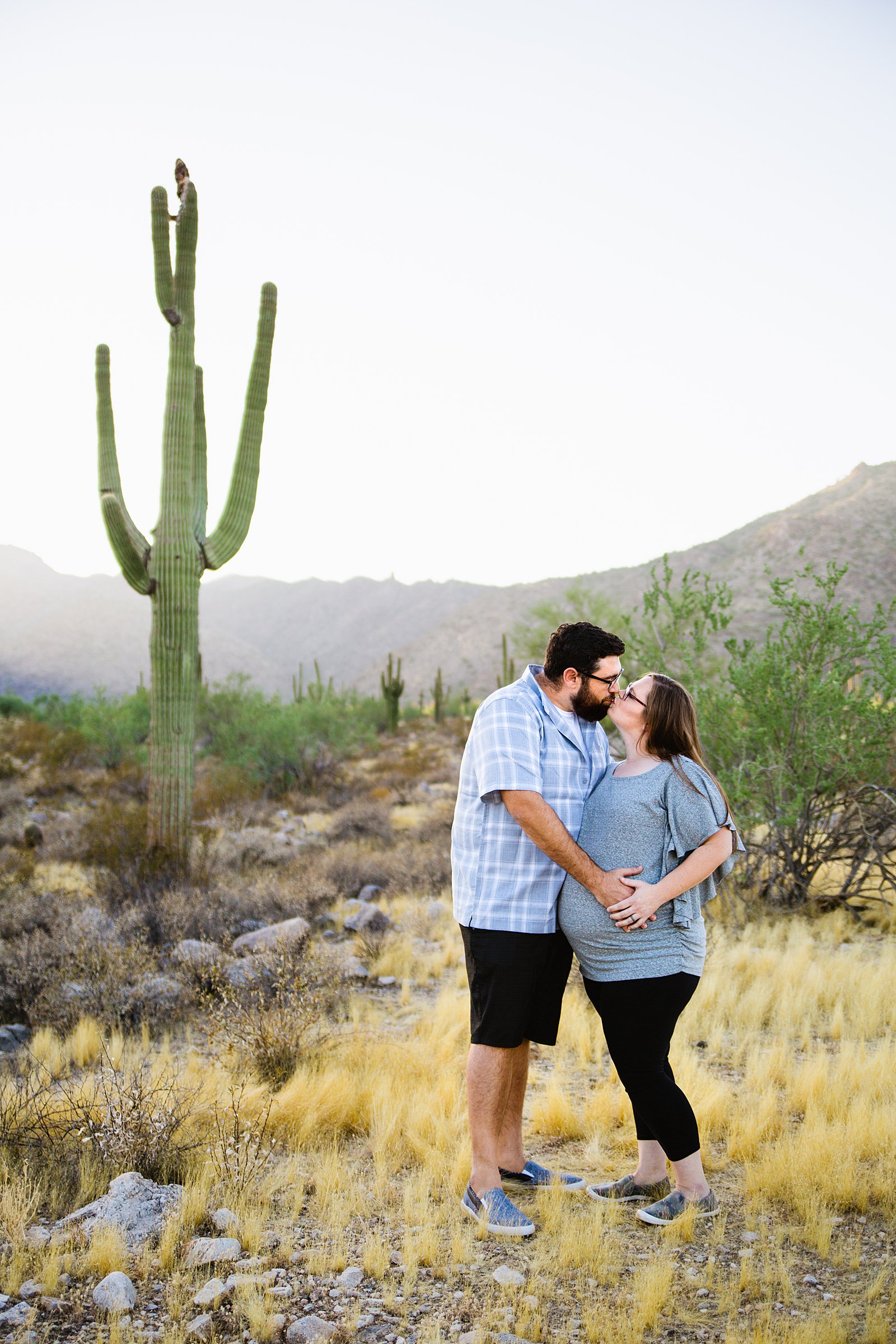 Couple kiss during their desert maternity session at the White Tanks by Phoenix maternity photographer PMA Photography.