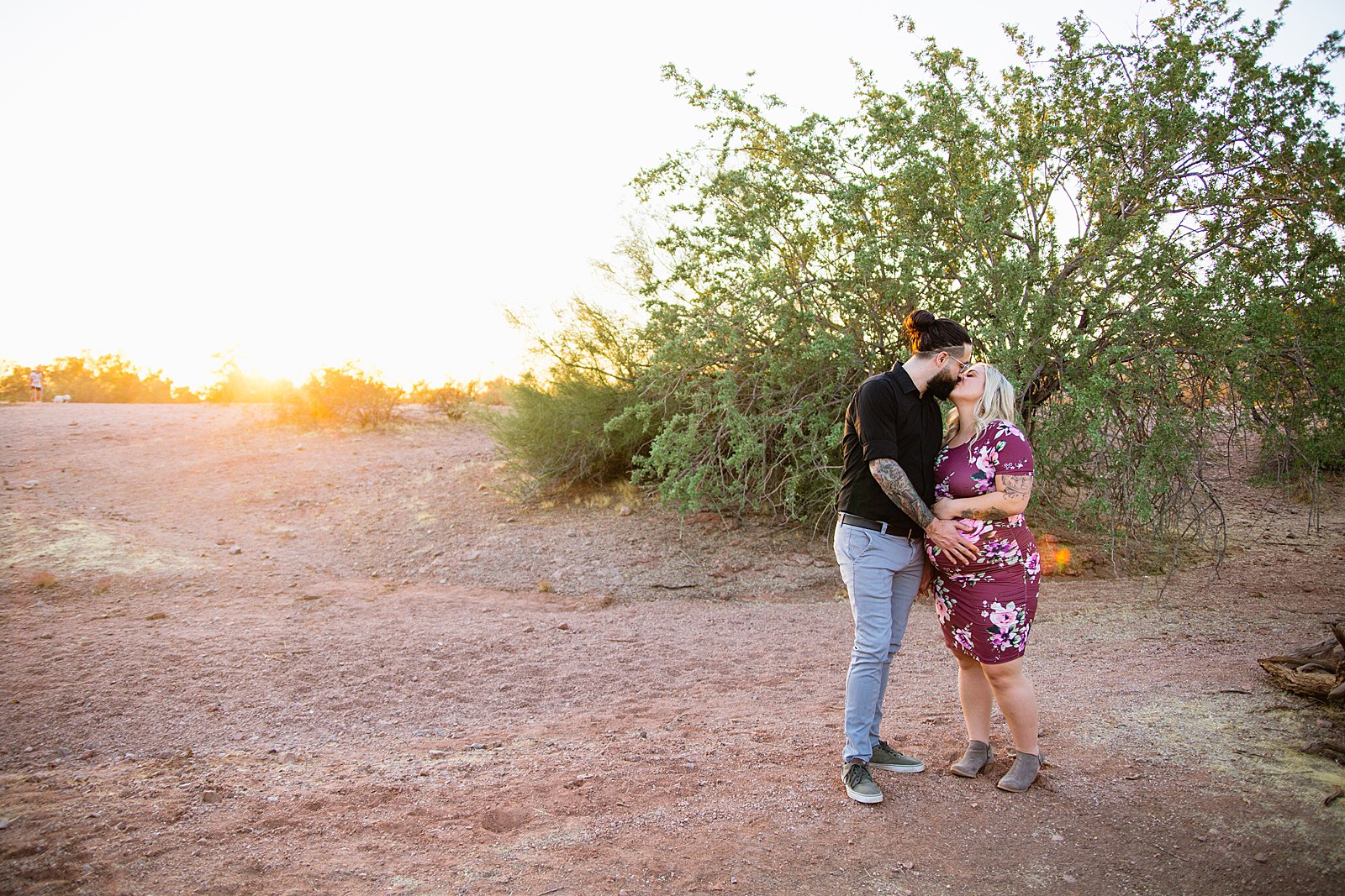 Couple share a kiss during their Phoenix maternity session by Arizona wedding photographer PMA Photography.