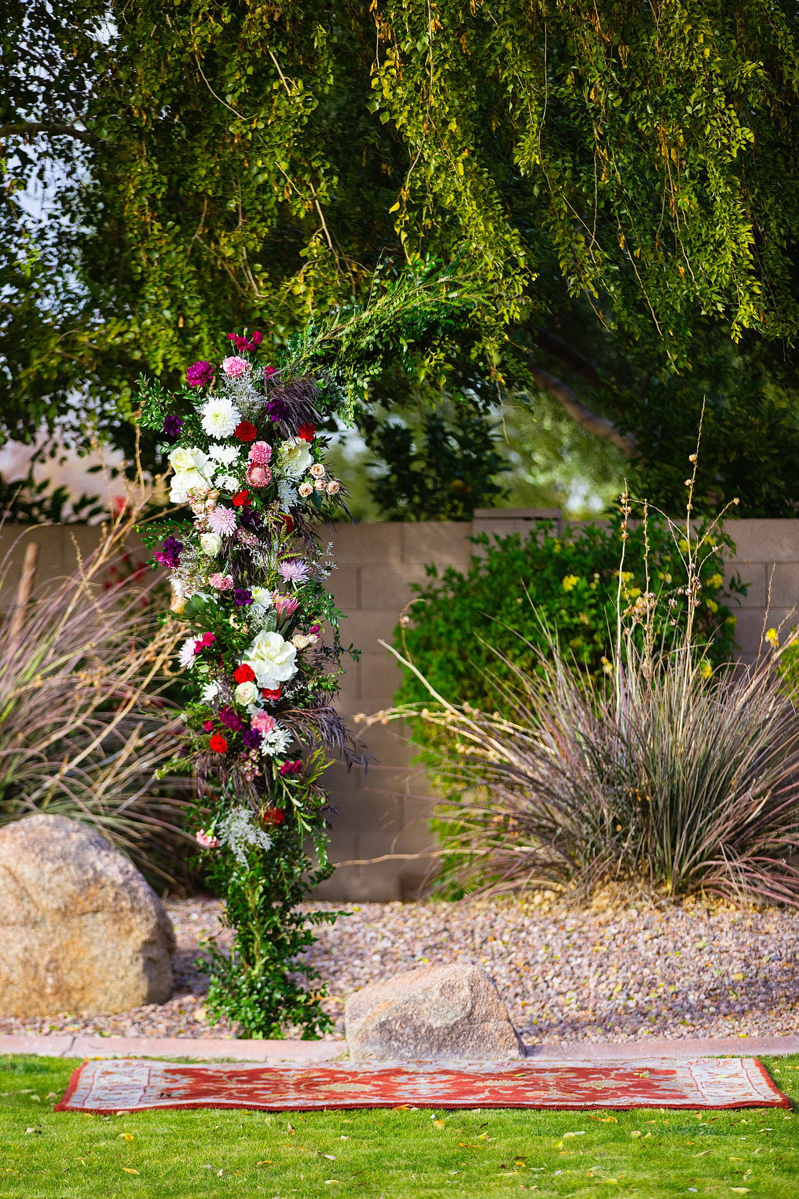 Lush and colorful floral wedding arch for a backyard wedding by Phoenix wedding photographer PMA Photography.