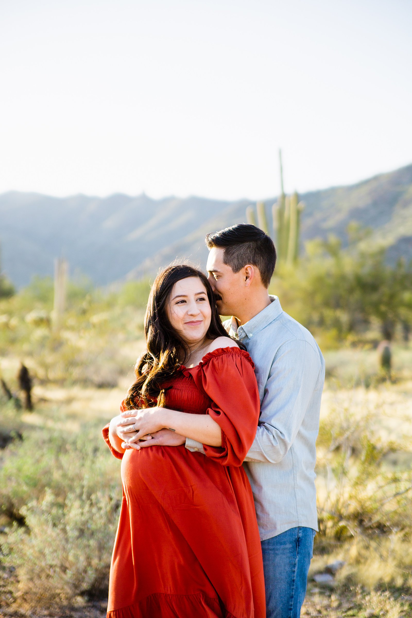 Couple share a kiss during their White Tanks maternity session by Phoenix wedding photographer PMA Photography.