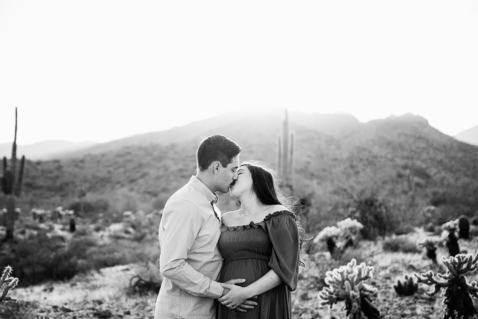 Couple share a kiss during their White Tanks maternity session by Phoenix wedding photographer PMA Photography.
