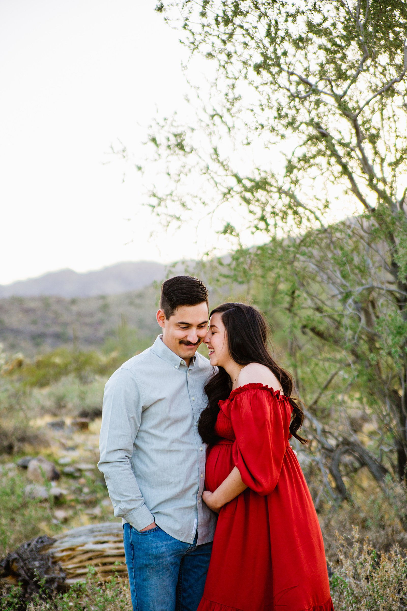 Couple laugh together during their Phoenix maternity session by Arizona engagement photographer PMA Photography.
