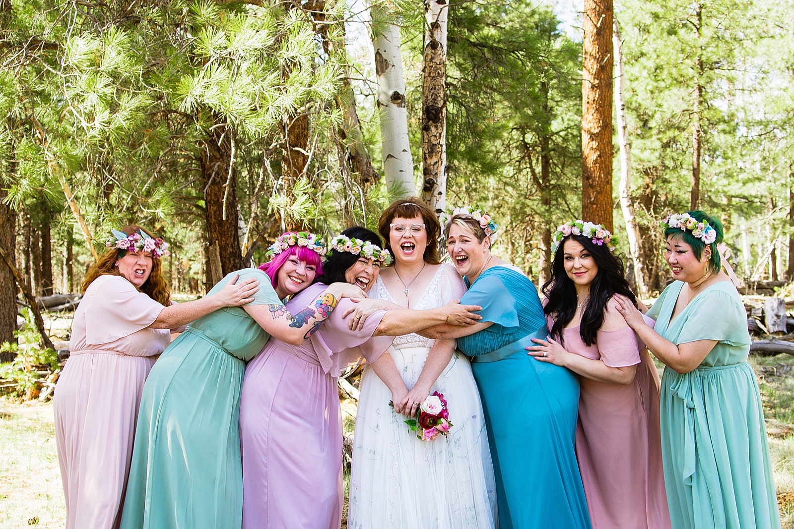 Bride and their wedding party laughing together at a Arizona Nordic Village wedding by Arizona wedding photographer PMA Photography.