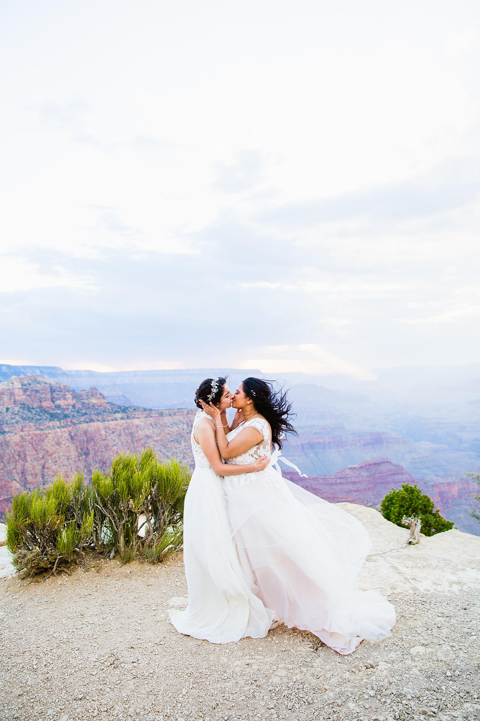 Lesbian couple share their first kiss during their wedding ceremony at Moran Point by Arizona elopement photographer PMA Photography.