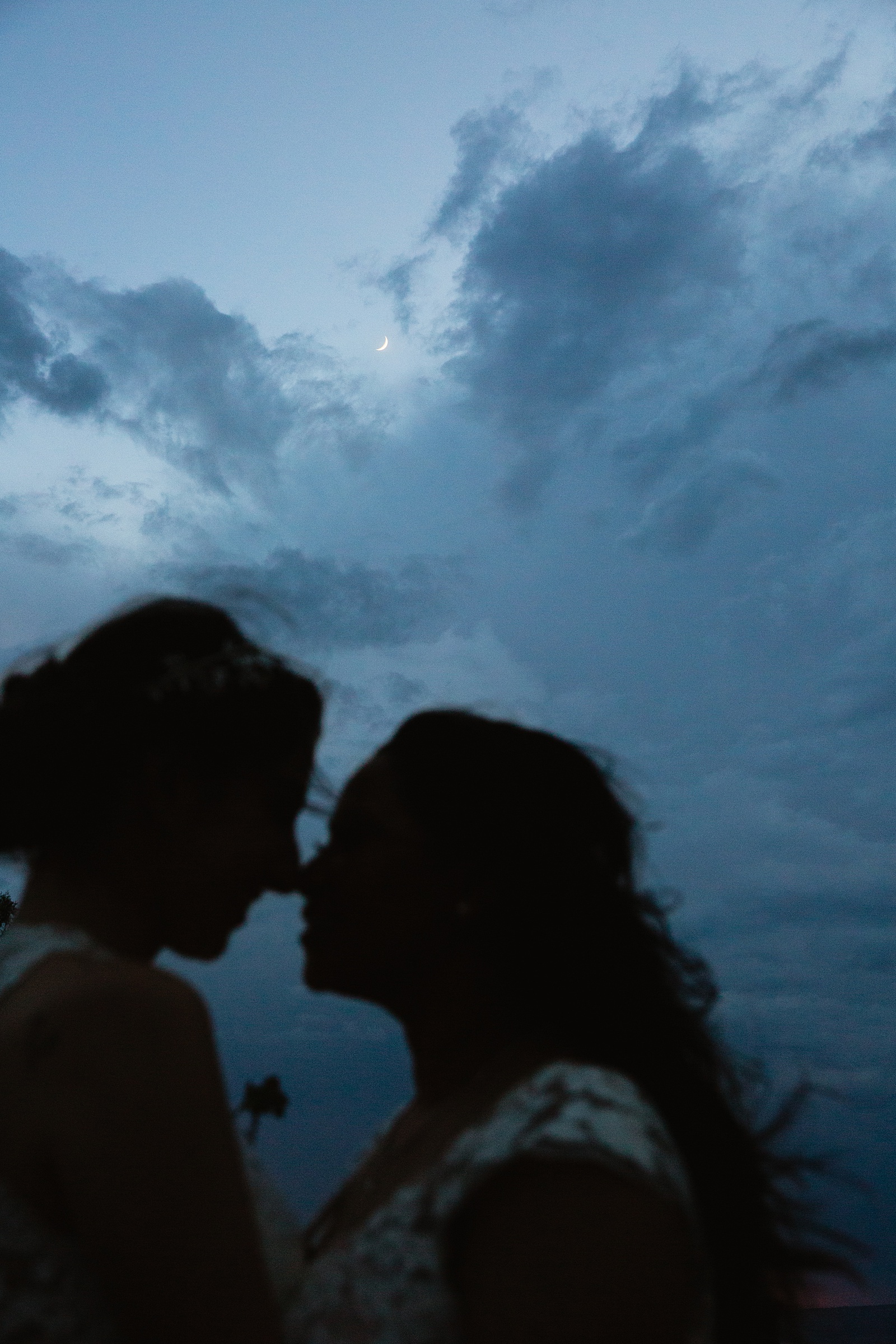 The moon silhouetted behind two brides at their Grand Canyon elopement.