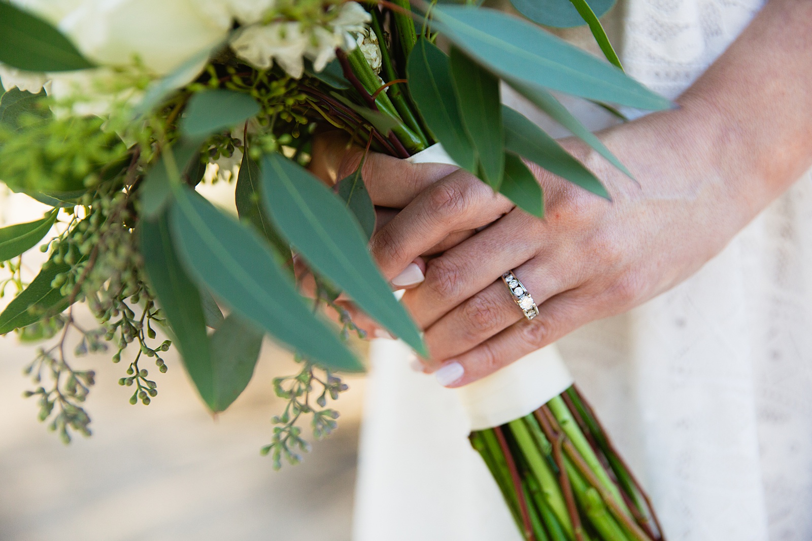 Bride's simple diamond and silver engagement ring holding her bouquet by PMA Photography.