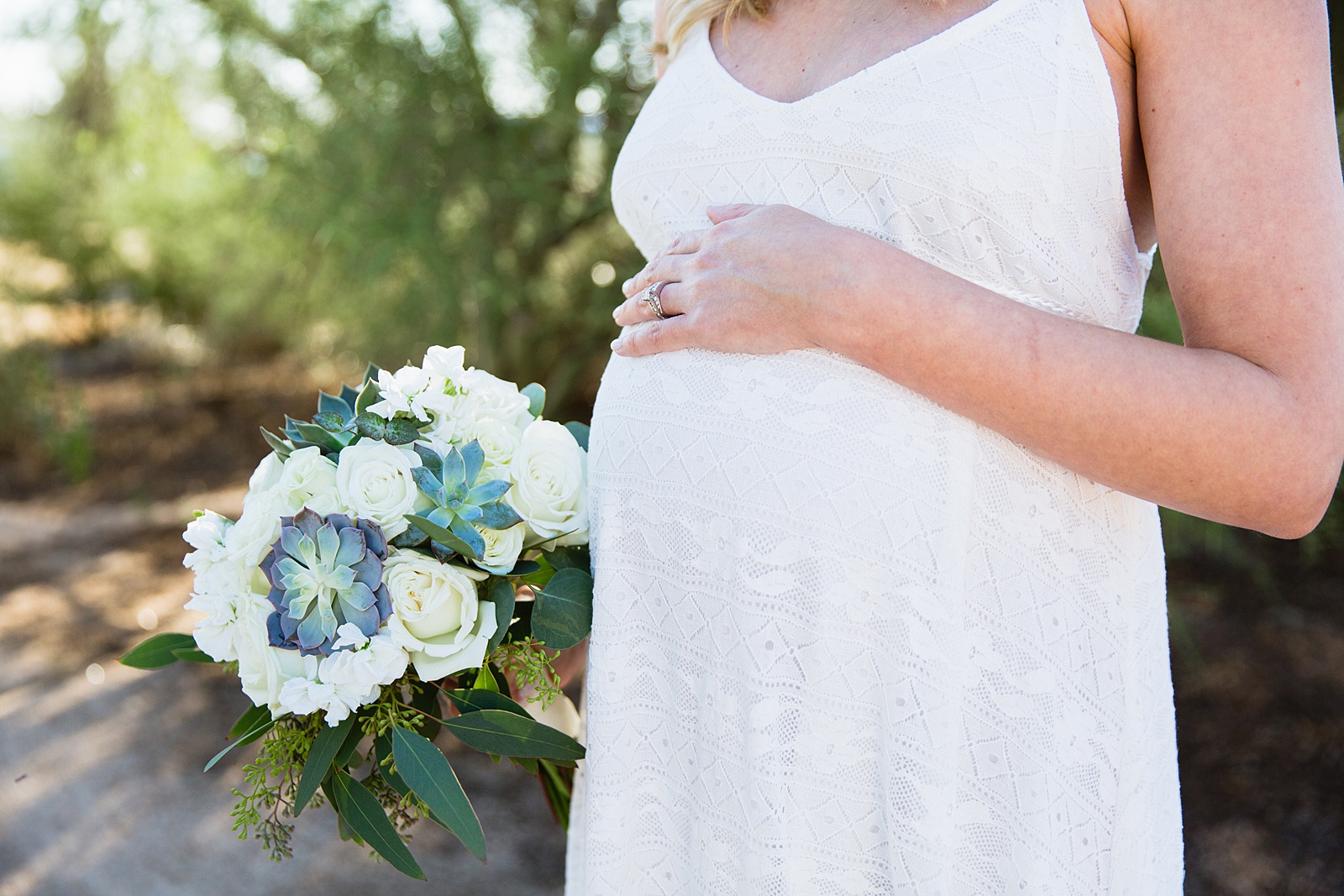 Pregnant bride cradling her baby bump while holding her white and green succulent bouquet by Arizona elopement photographer PMA Photography.