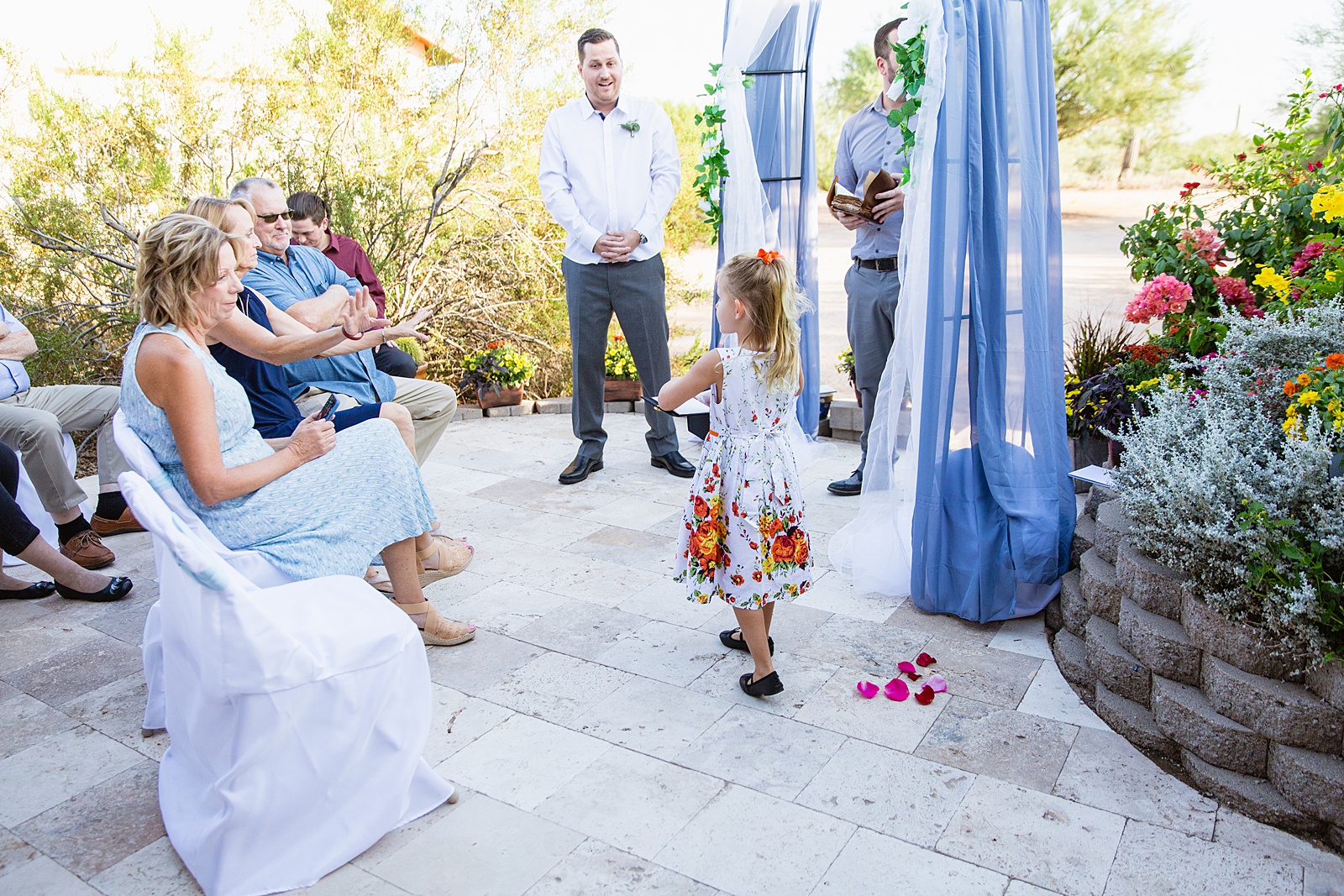 Flower girl walking down aisle during a backyard wedding ceremony by Phoenix wedding photographer PMA Photography.