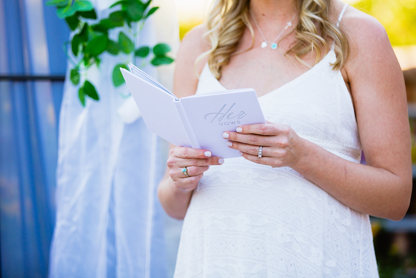 Close up image of a brides wedding vow book showing off her baby bump for their backyard elopement by Arizona wedding photographer PMA Photography.