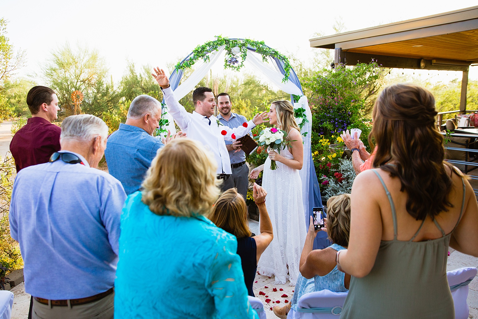 Guests throwing flowers after the first kiss during a backyard elopement by Phoenix wedding photographer PMA Photography.