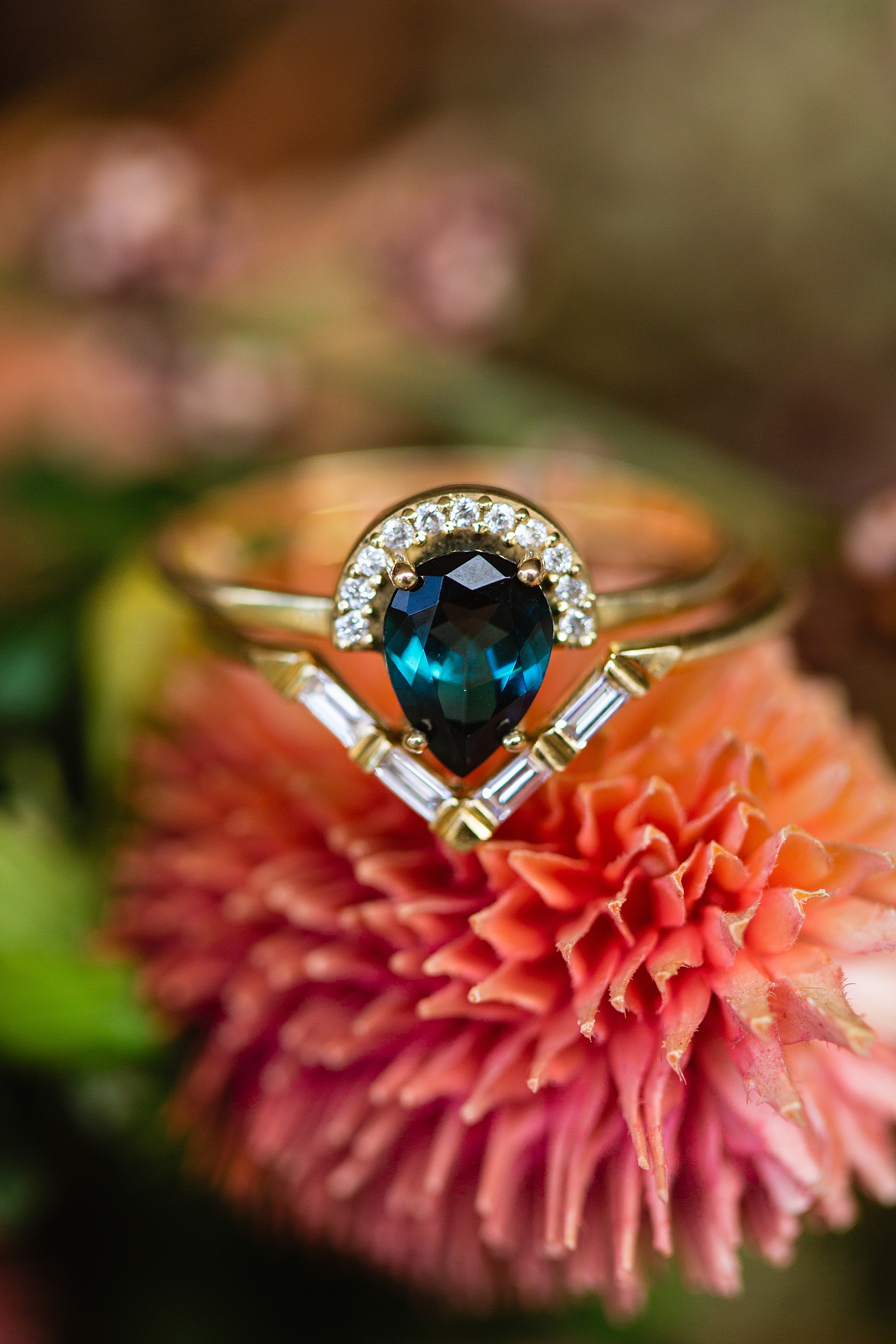 Unique emerald wedding ring set on top of peach and navy dried floral bridal bouquet by Phoenix wedding photographer PMA Photography.