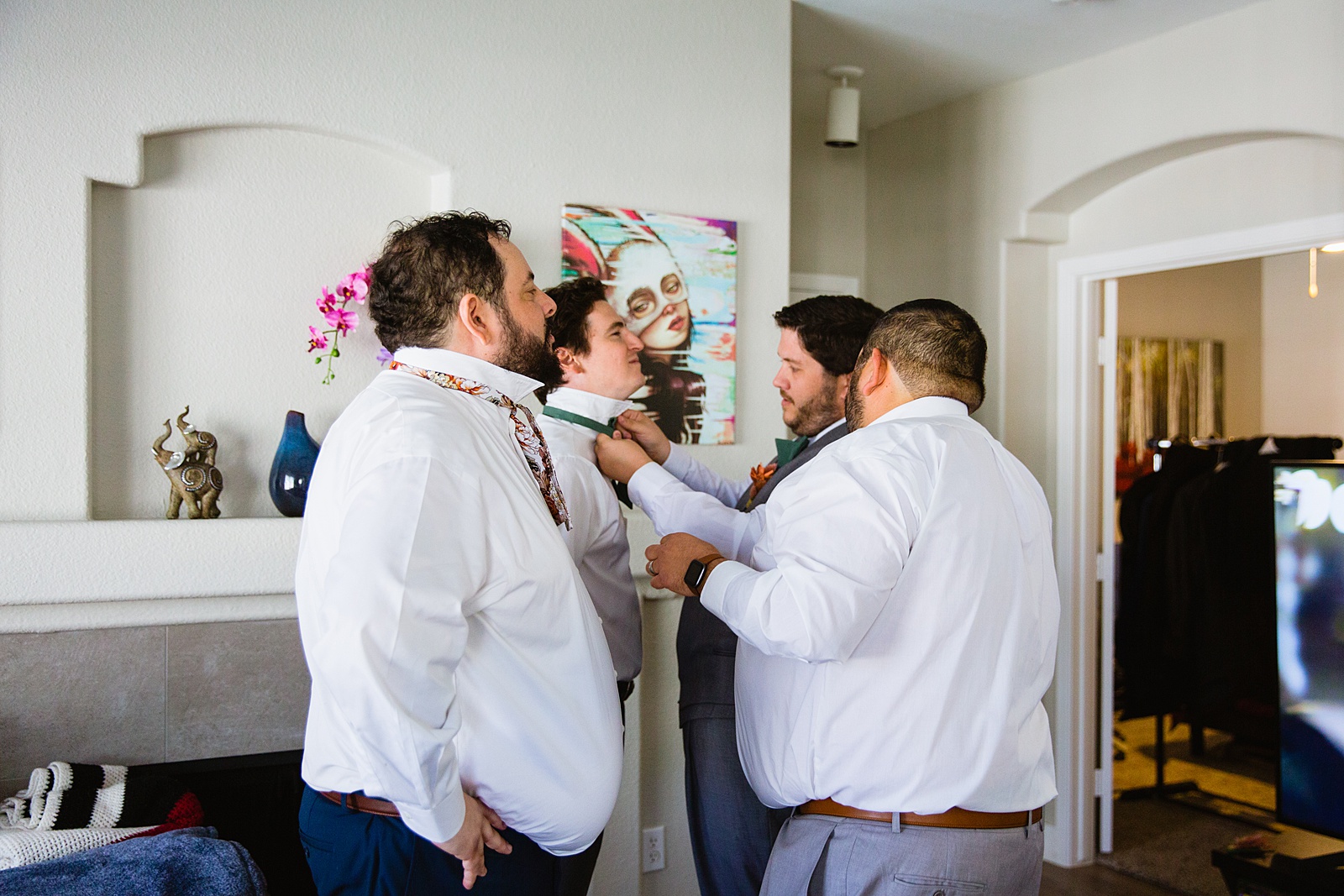 Groomsmen showing the other groomsmen how to tie a bowtie by PMA Photography.