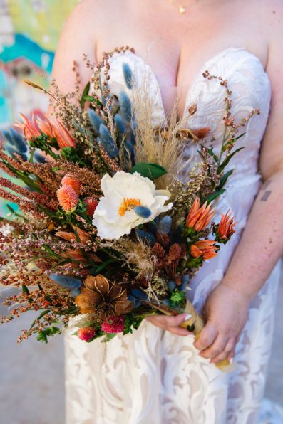 Bride's colorful peach and blue dried floral bouquet by PMA Photography.
