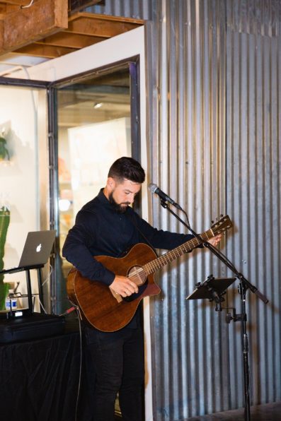 Ceremony musician playing guitar and singing as the wedding party and bride walk down the aisle by Phoenix wedding photographer PMA Photography.