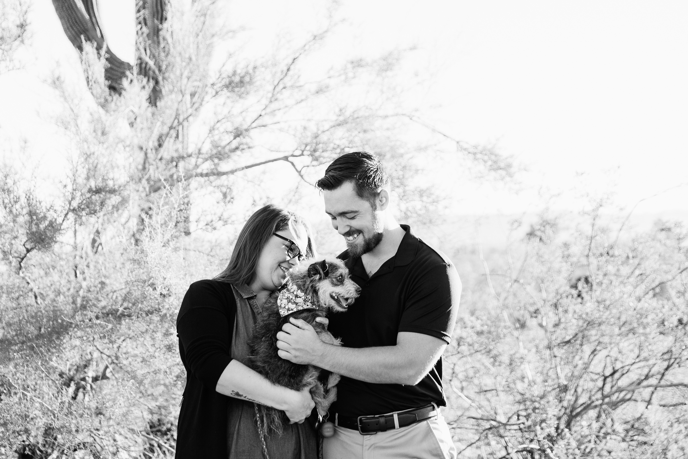 Couple laugh together with their dog during their Phoenix engagement session by Arizona engagement photographer PMA Photography.