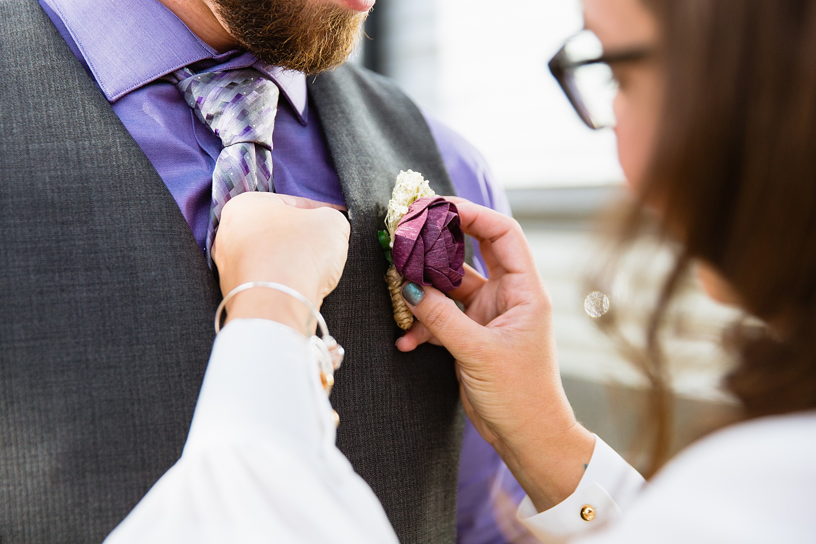 Bride helping her groom put on his boutonniere for their elopement by Arizona elopement photographers PMA Photographer