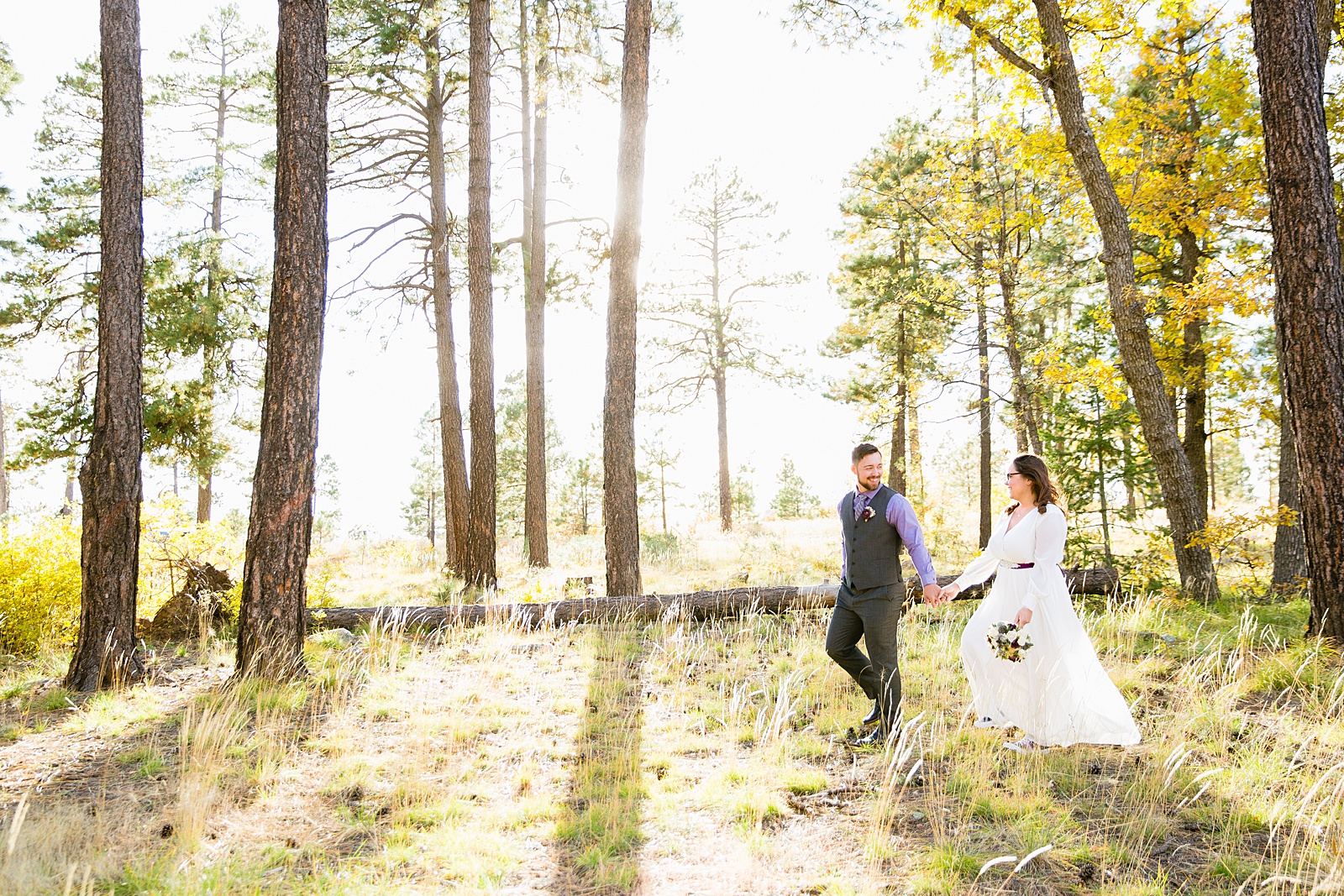Bride and Groom walking together through the forest during their Mogollon Rim elopement by Arizona elopement photographer PMA Photography.