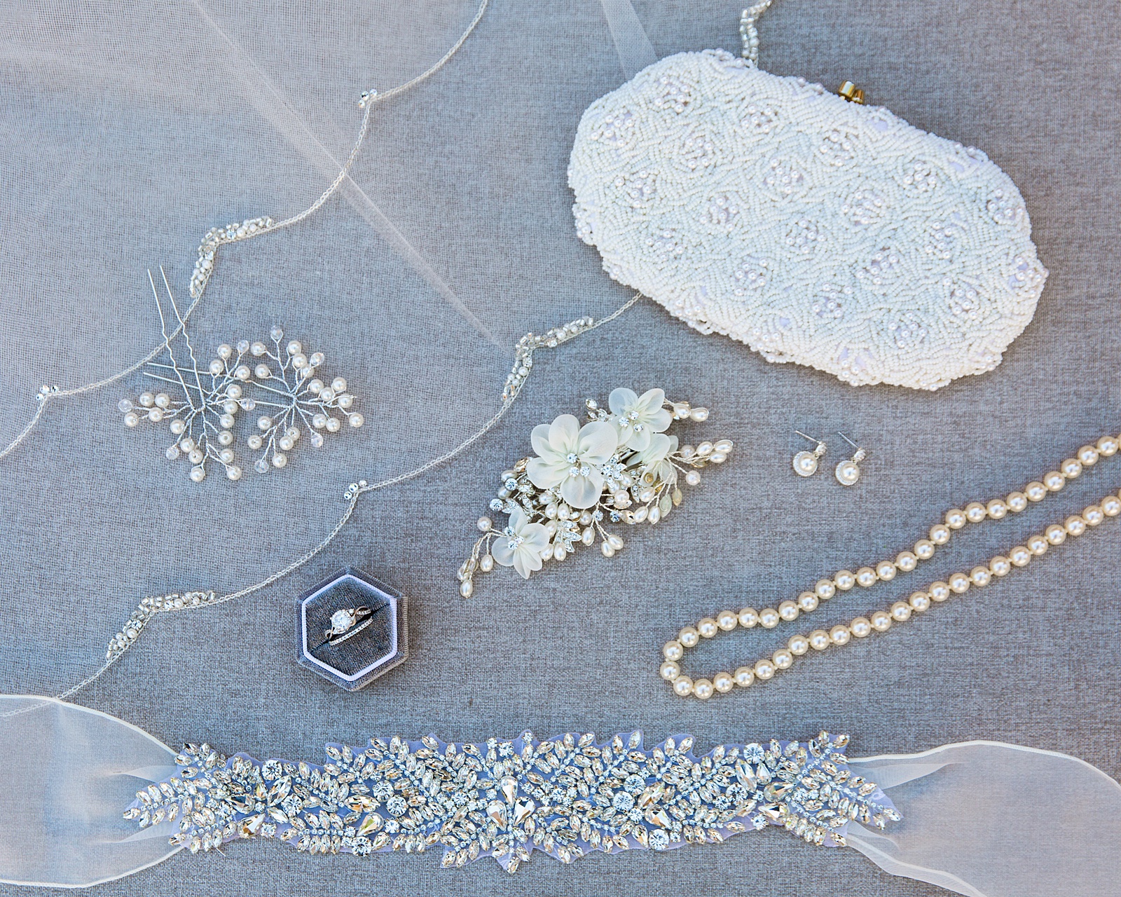 Bride's white wedding day details including a crystal sash and pearl jewelry by PMA Photography.