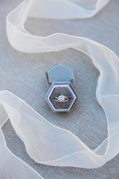 Bride's white gold and diamond wedding ring in a grey ring box with white ribbon by Phoenix wedding photographer PMA Photography.