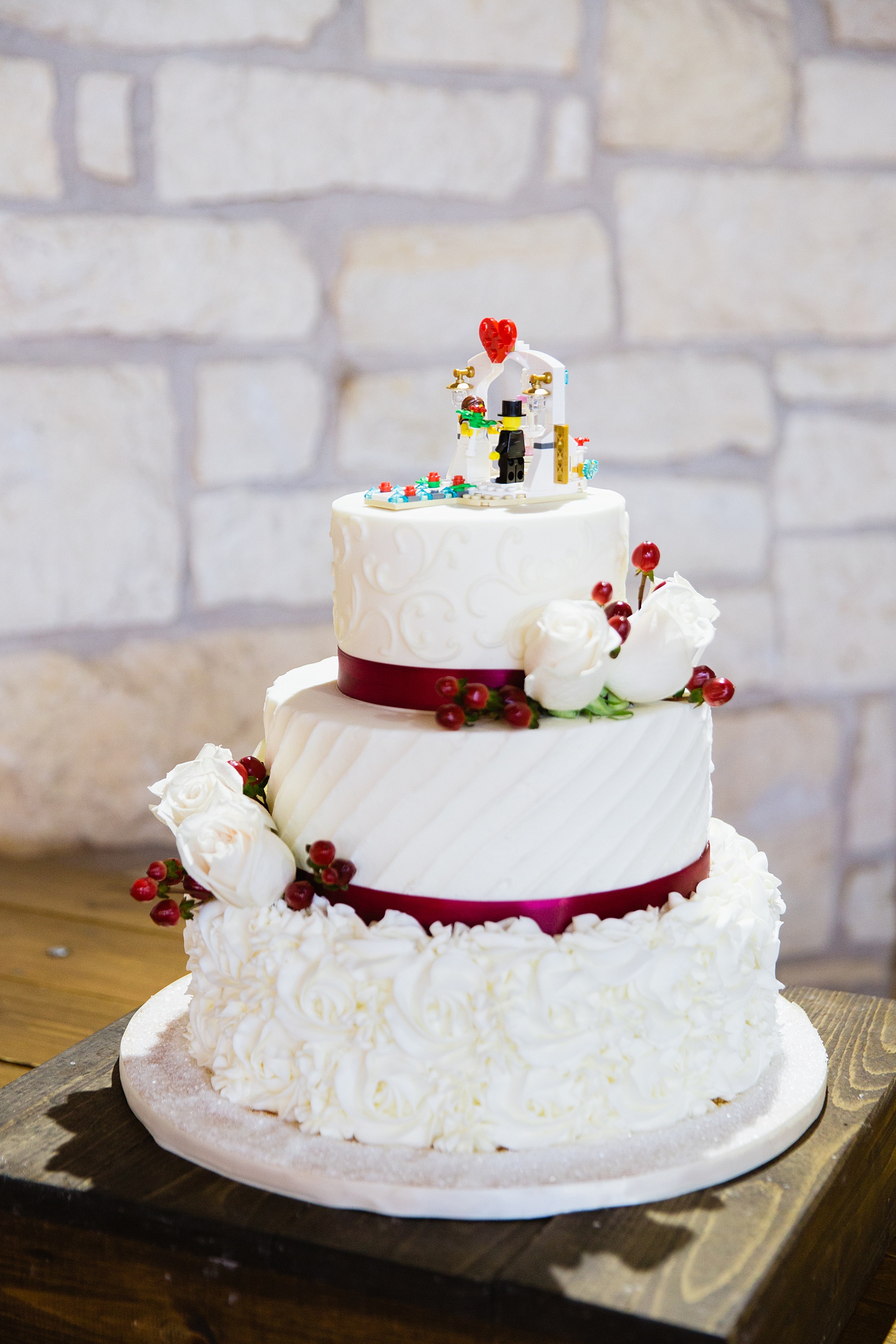 White and red wedding cake with lego bride and groom cake topper by Arizona wedding photographer PMA Photography.