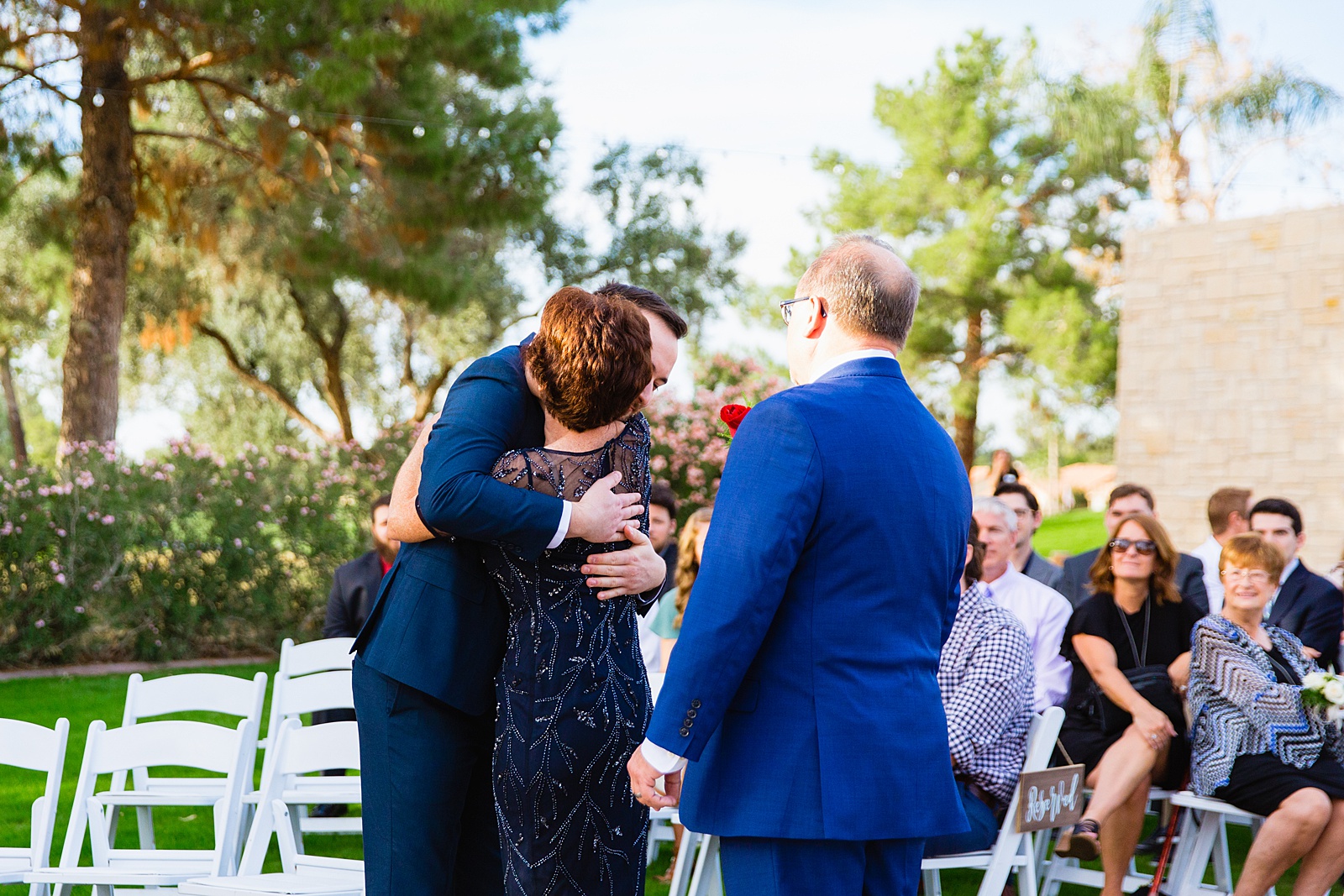Groom hugging his parents at the end of the aisle at their Ocotillo Oasis wedding ceremony by Arizona wedding photographer PMA Photography.