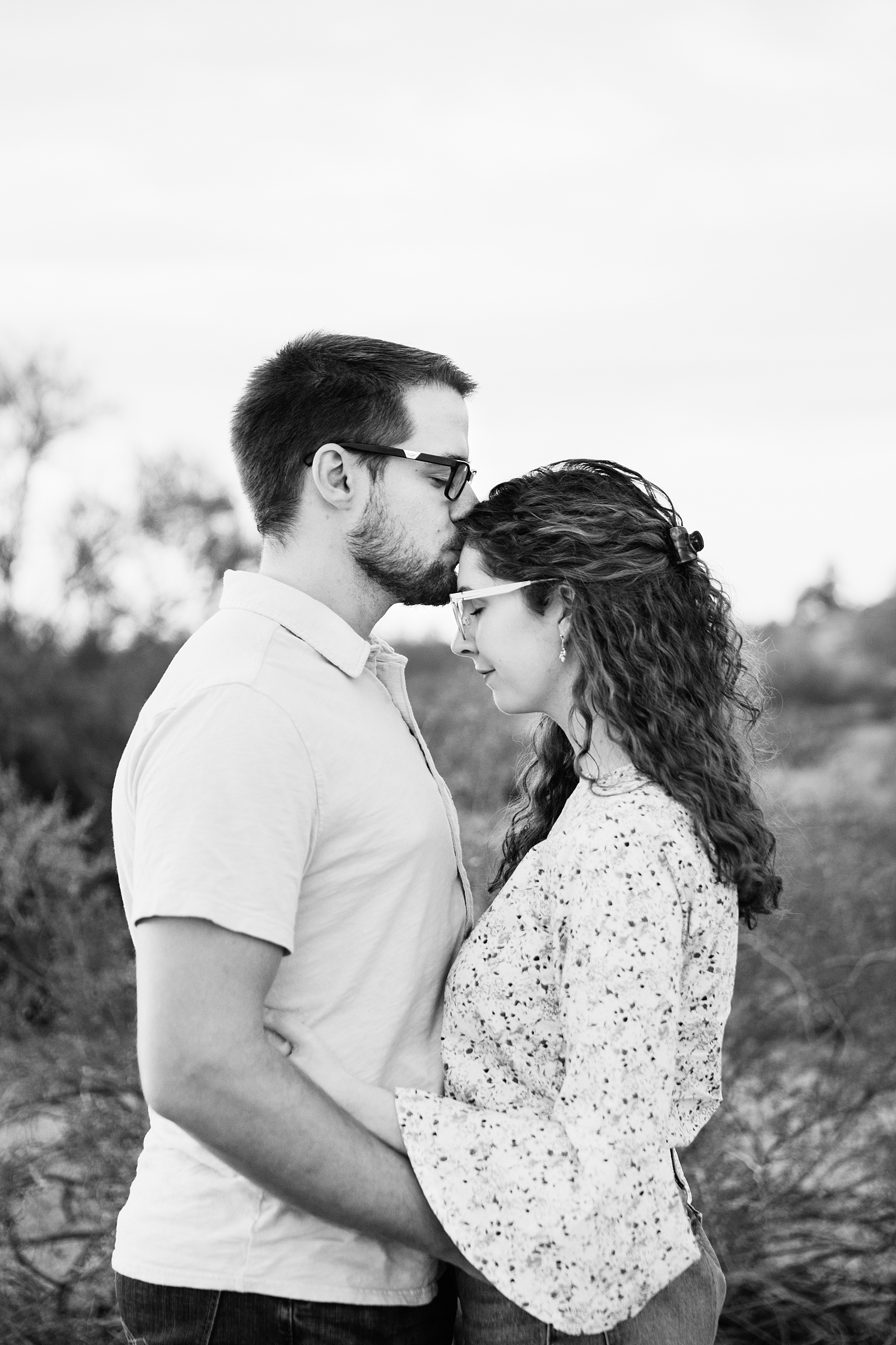 Man kissing fiancé's forehead during their Phoenix engagement session by Arizona wedding photographer PMA Photography.