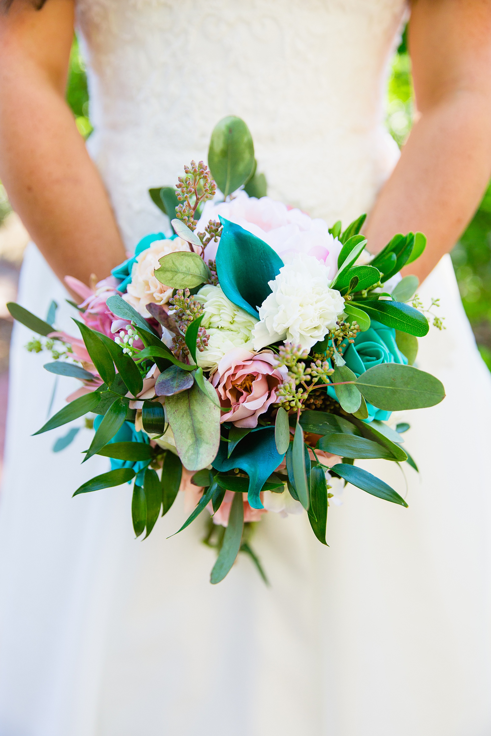 Bride's pink and teal wedding bouquet with mixed faux flowers and real flowers and greenery by PMA Photography.