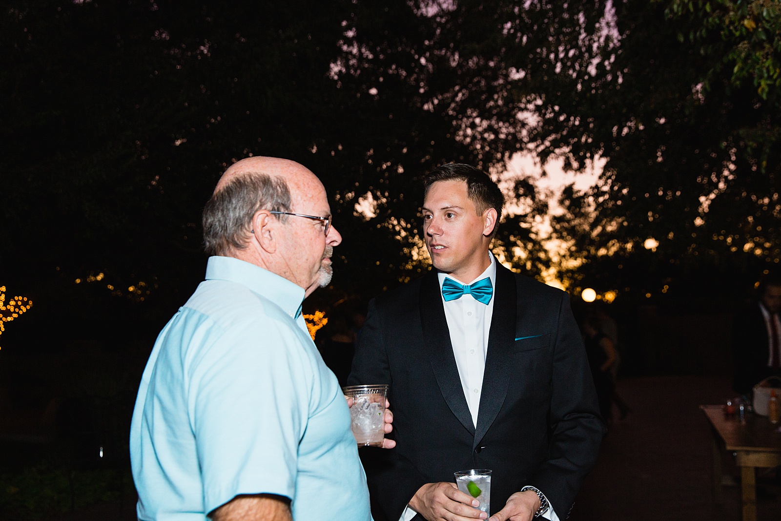 Candid photo of groom talking with guests during cocktail hour by Mesa wedding photographer PMA Photography.