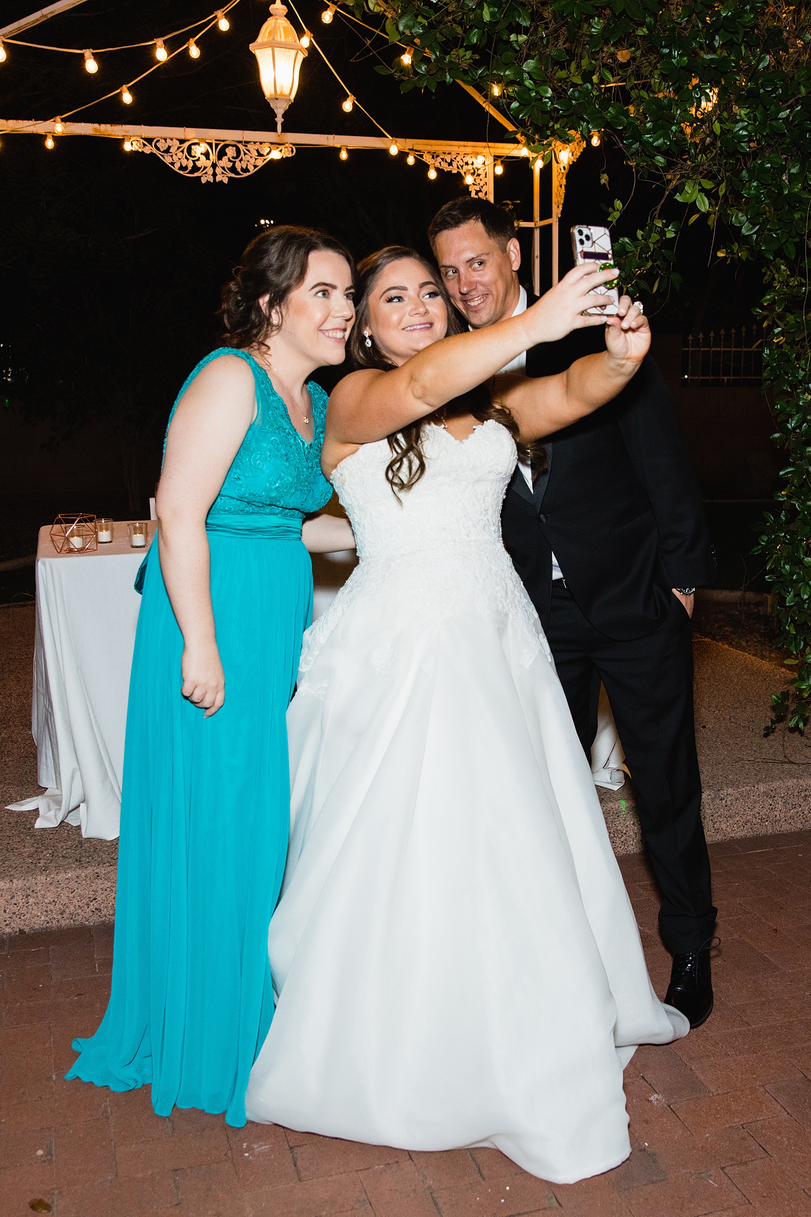 Bride taking a selfie with her groom and bridesmaid by Phoenix wedding photographer PMA Photography.