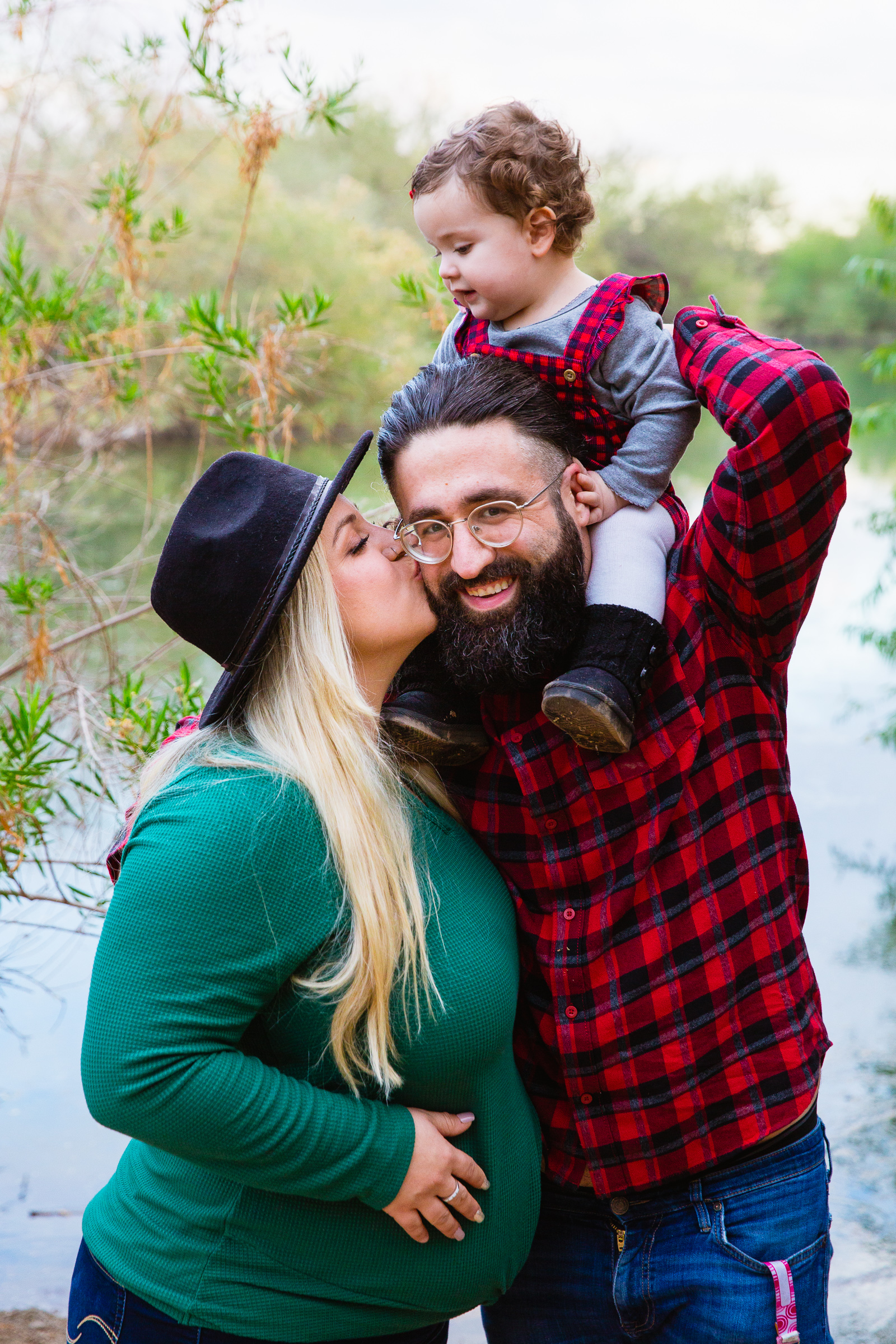 Mom kisses dad on the cheek for their Riparian Preserve at Water Ranch family session by Gilbert family photographer PMA Photography.