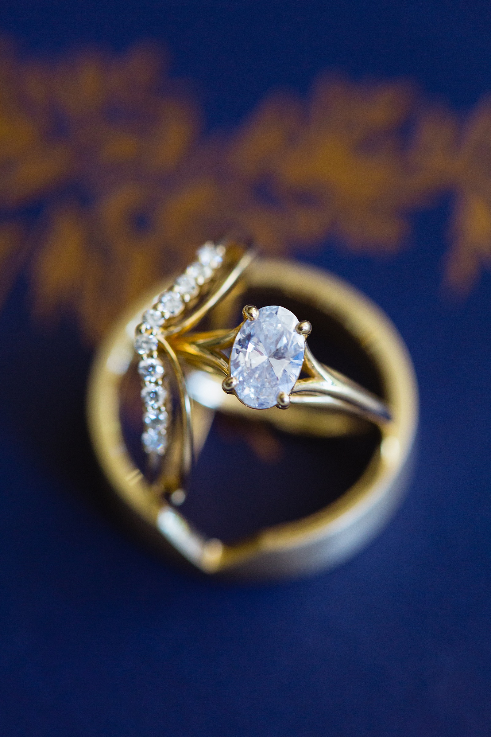 Custom gold and diamond wedding rings on navy and copper wedding stationary by Arizona wedding photographer PMA Photography.