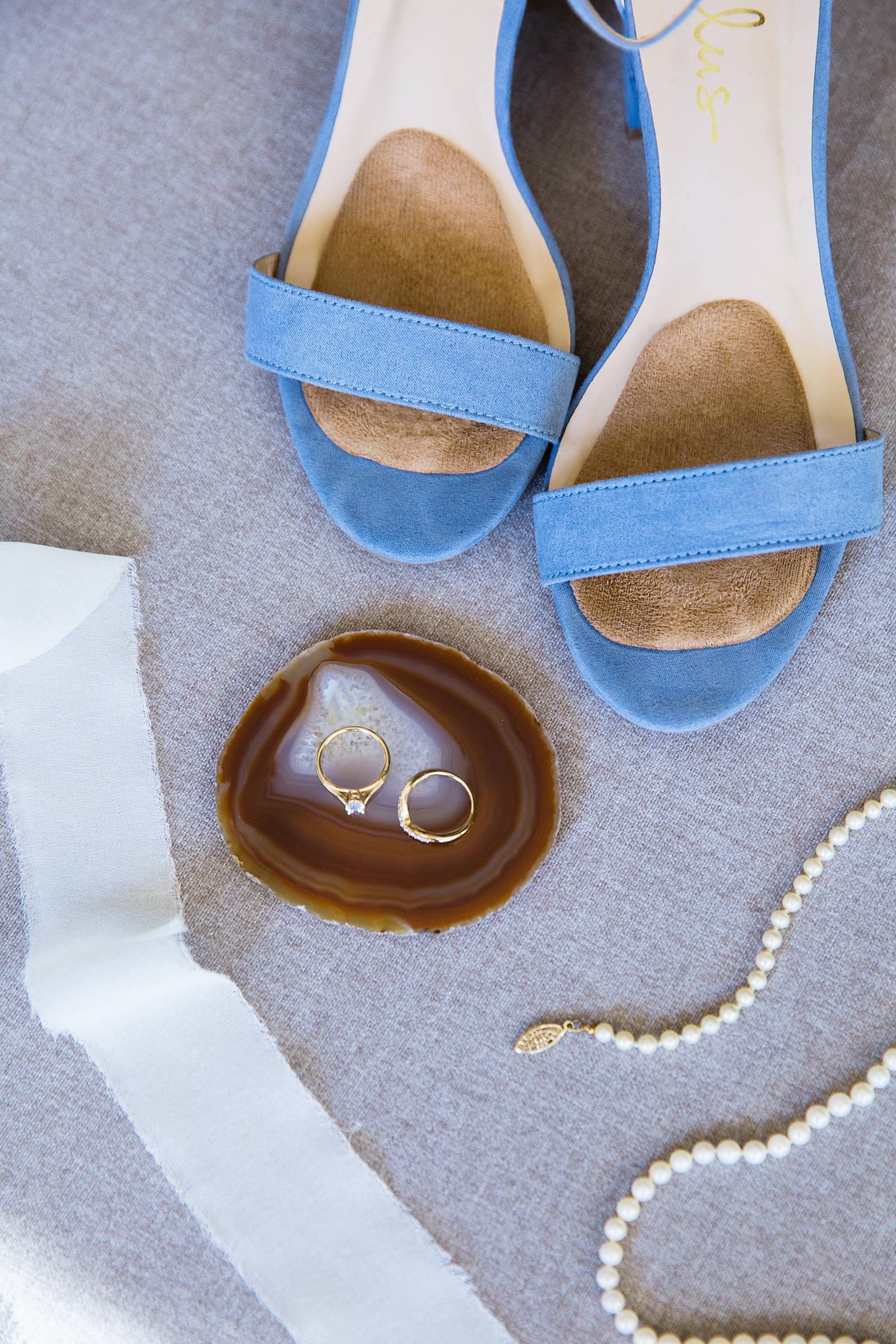 Brides's wedding day details of pearls and light blue shoes by PMA Photography.
