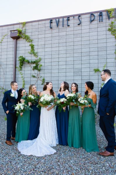 Bride and mixed gender bridal party laughing together at a Papago Events wedding by Arizona wedding photographer PMA Photography.