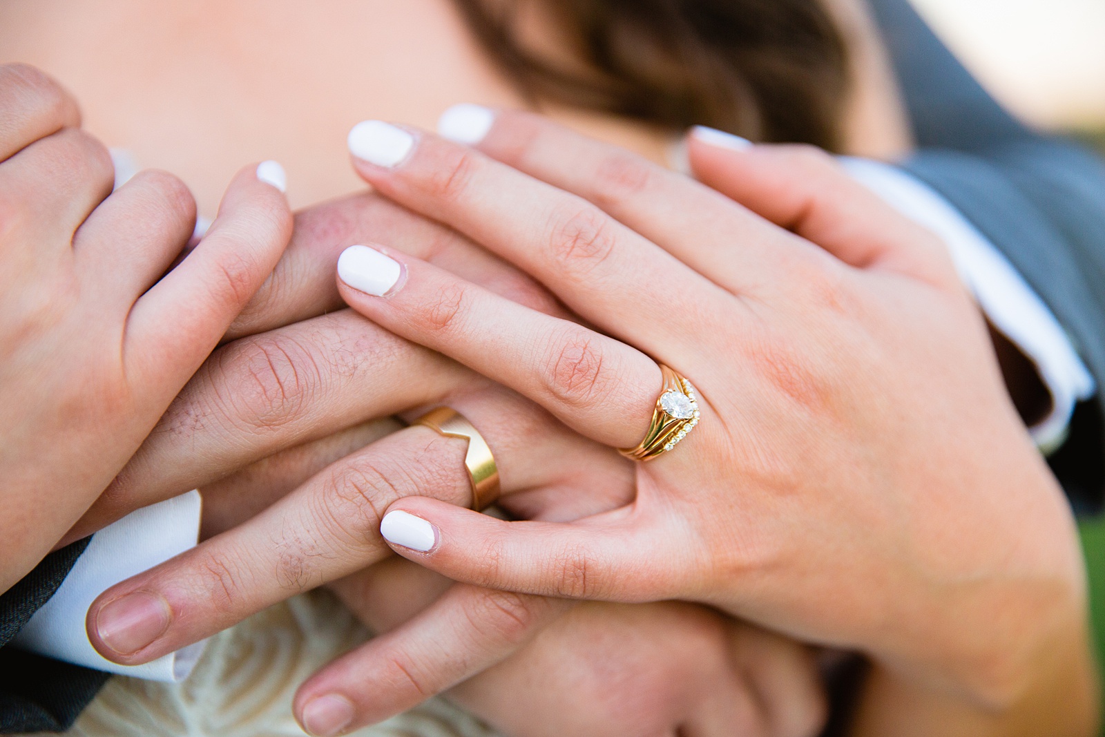 Unique gold wedding bands on the couple's hands by Arizona wedding photographer PMA Photography.