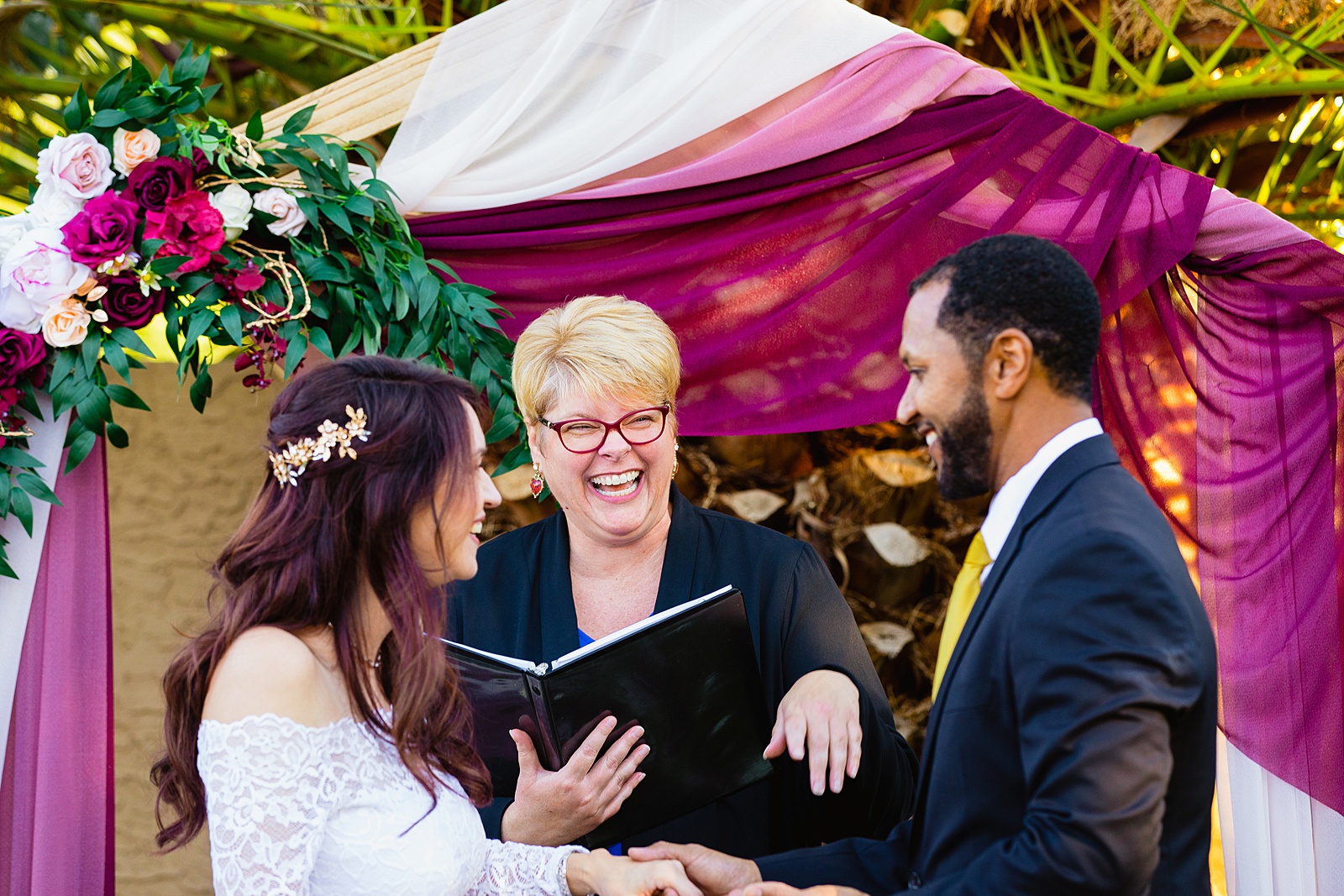 Officiant laughing with couple during their ceremony by PMA Photography.