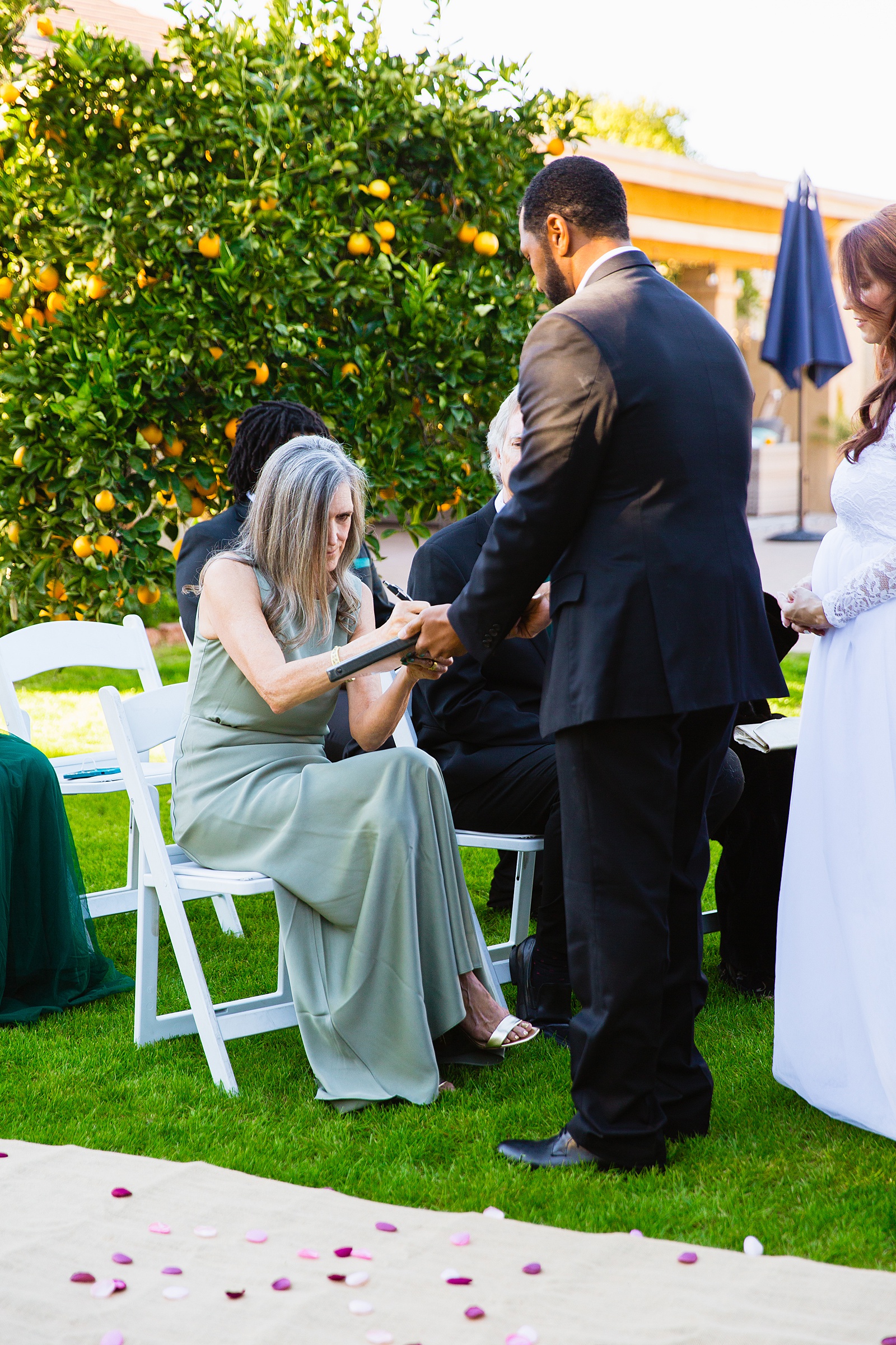Mother of the bride signing the marriage license by PMA Photography.