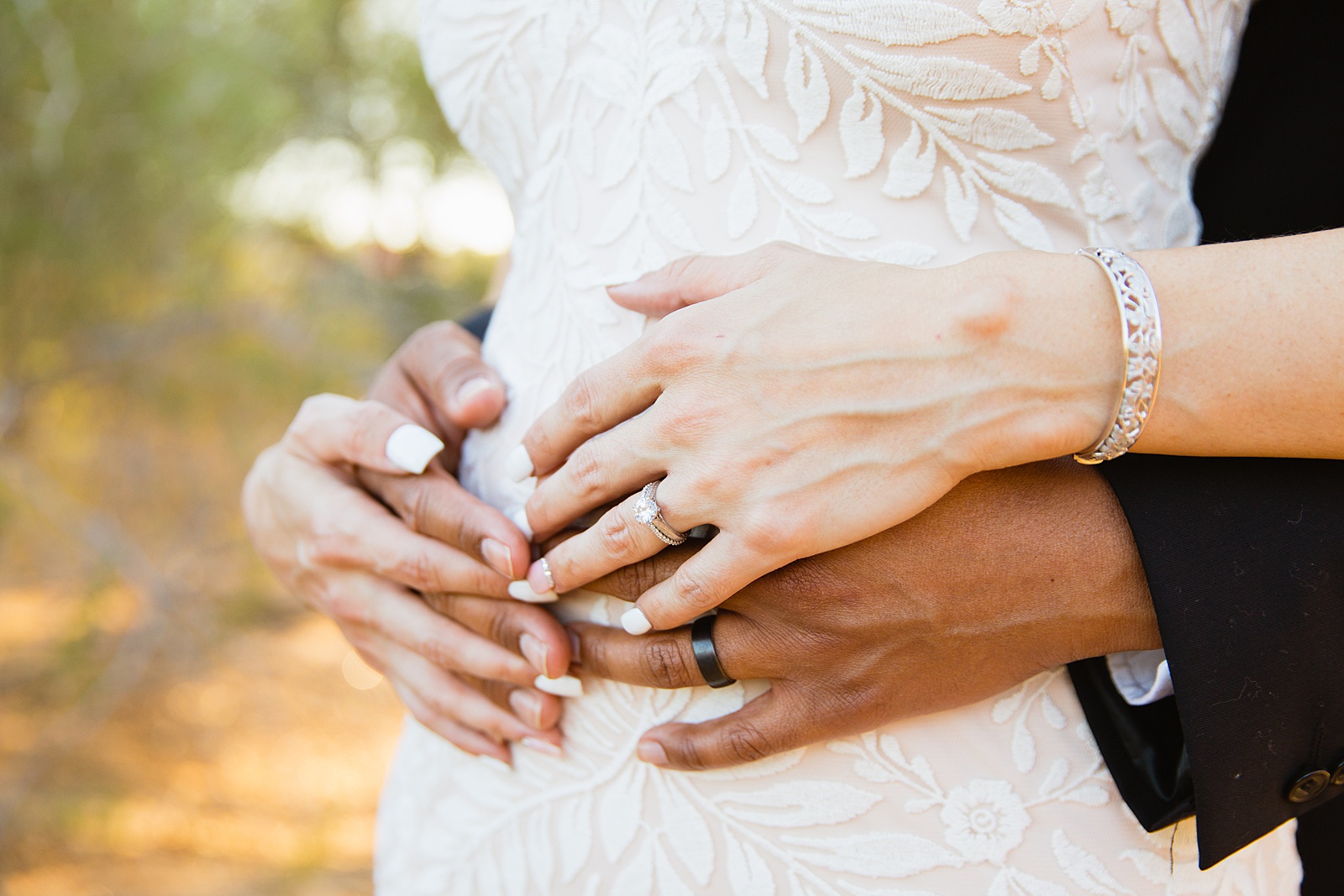 Bride and groom's wedding rings on top of the bride's pregnant belly by PMA Photography.