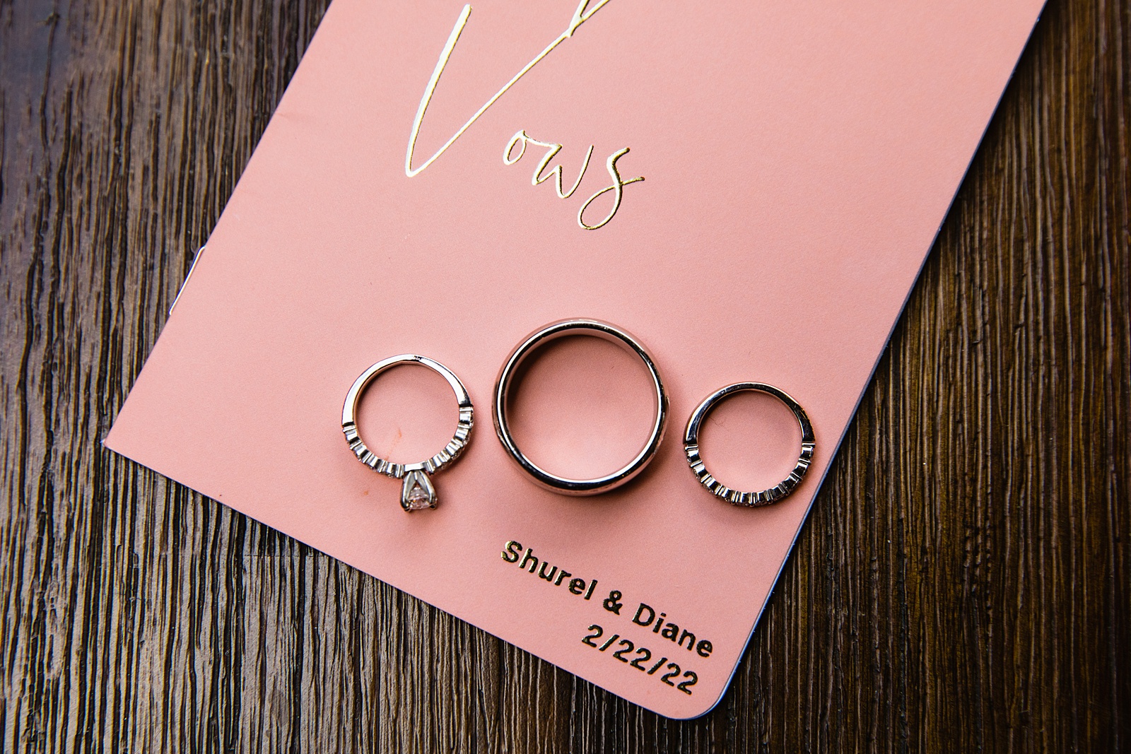 Couple's wedding rings on custom peach vow books by PMA Photography.