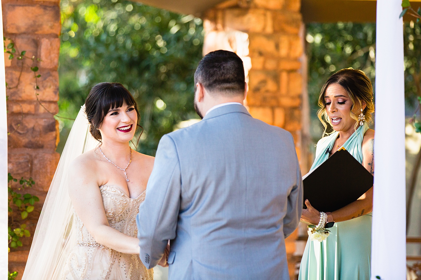 Bride looking at her groom during their wedding ceremony at Bella Rose Estate by Chandler wedding photographer PMA Photography.