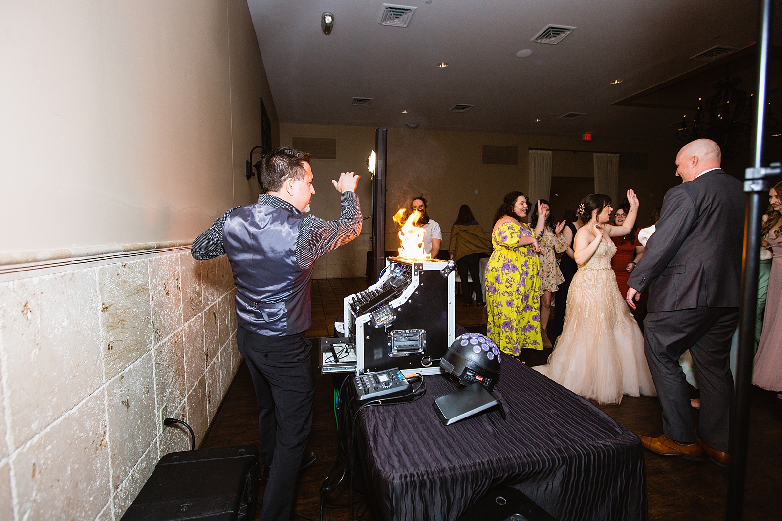 DJ doing tricks with fire while guests dance by Arizona wedding photographer PMA Photography.