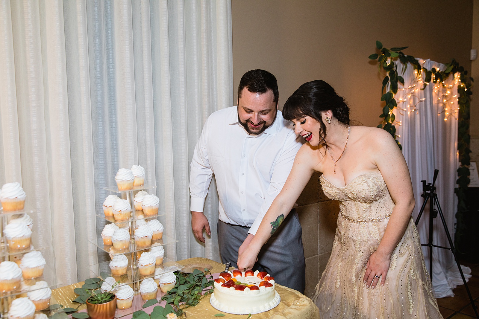 Bride and Groom cutting their wedding cake at their Bella Rose Estate wedding reception by Arizona wedding photographer PMA Photography.