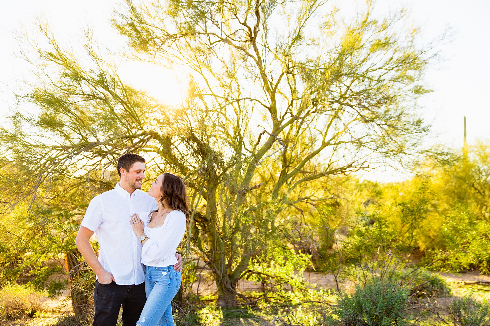 Couple look at each other during their desert engagement session by Phoenix wedding photographer PMA Photography.